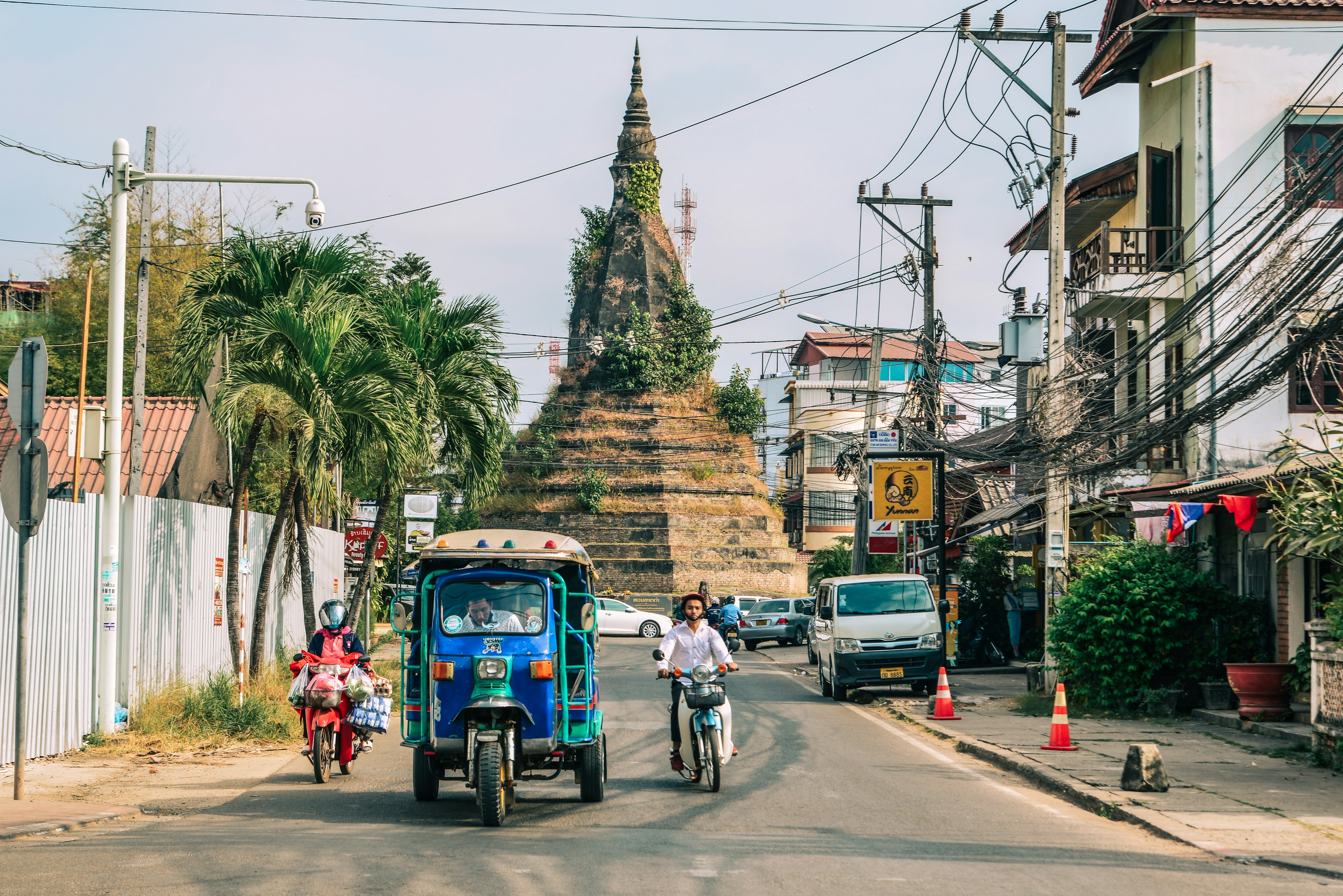 A tuk-tuk taxi drives down a street in Vientiane, Laos