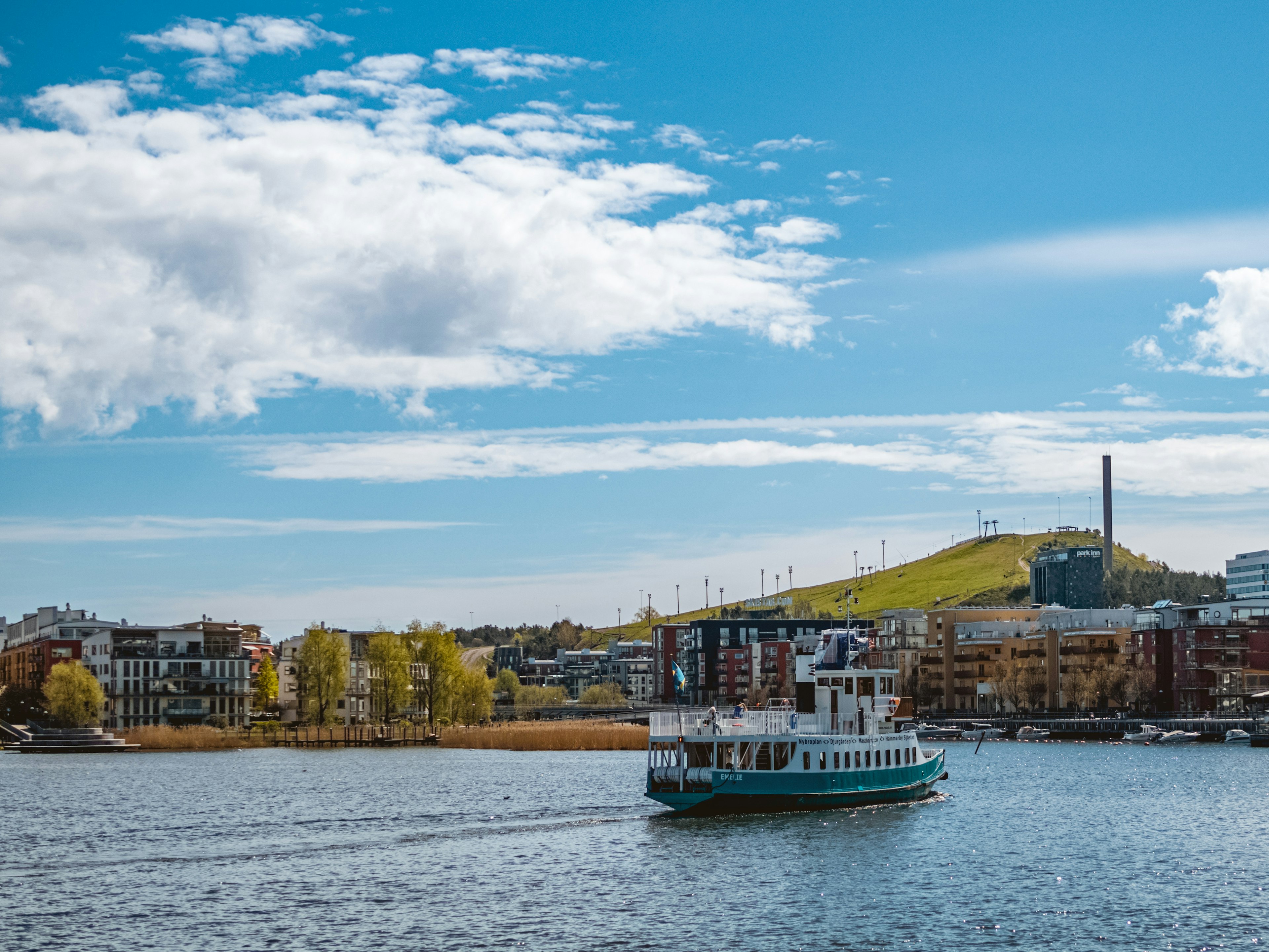 A ski slope viewed across a body of water with a passenger ferry in the foreground