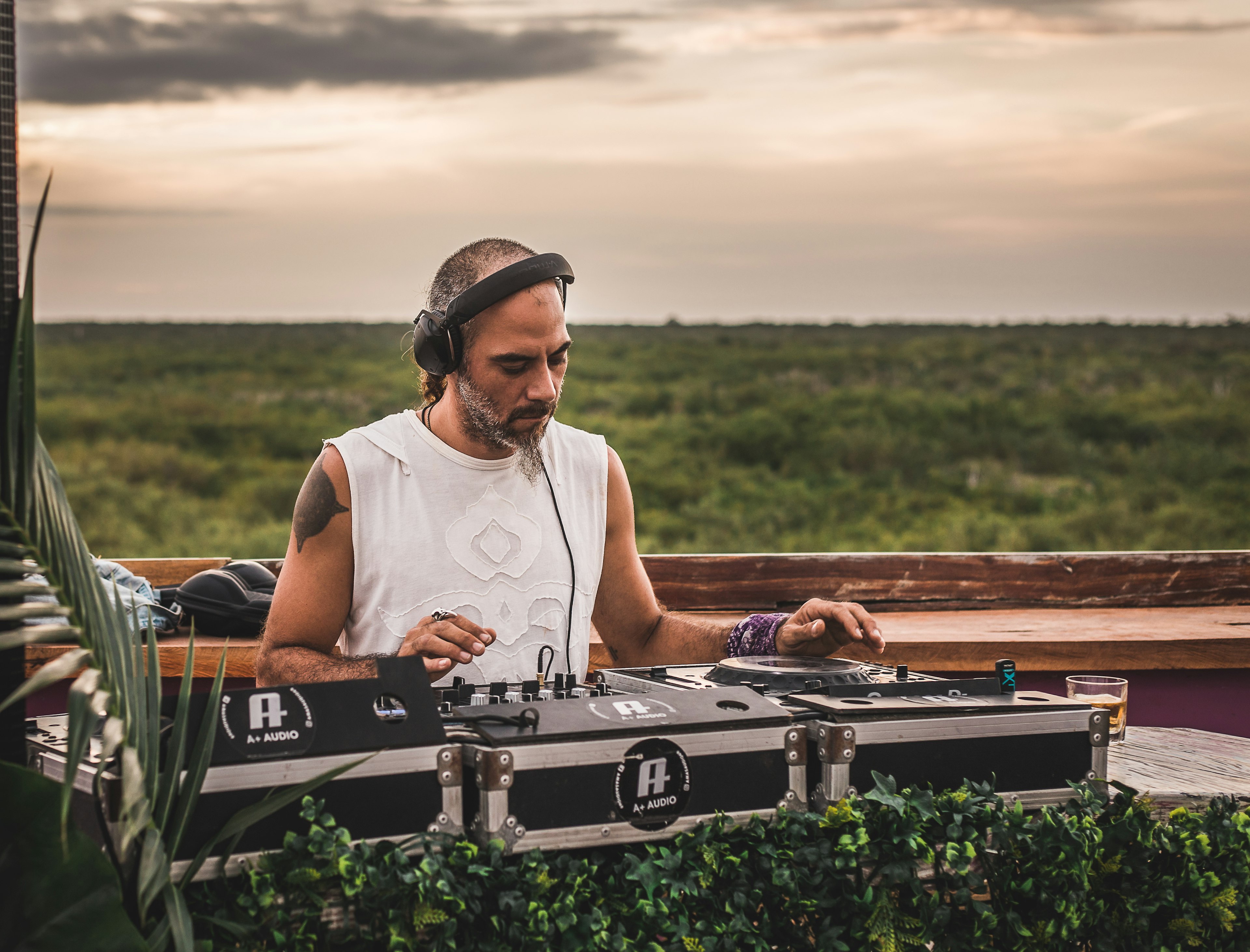 A DJ at a rooftop bar at sunset overlooking the jungle near Tulum