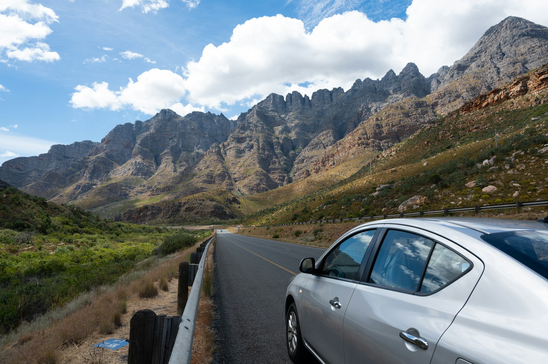 A silver car drives on a curvy road through rocky mountains in South Africa