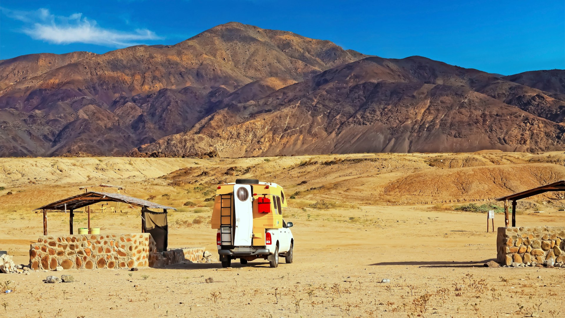 A camper can sits in the orange desert looking out at a mountain. Atacama, Chile