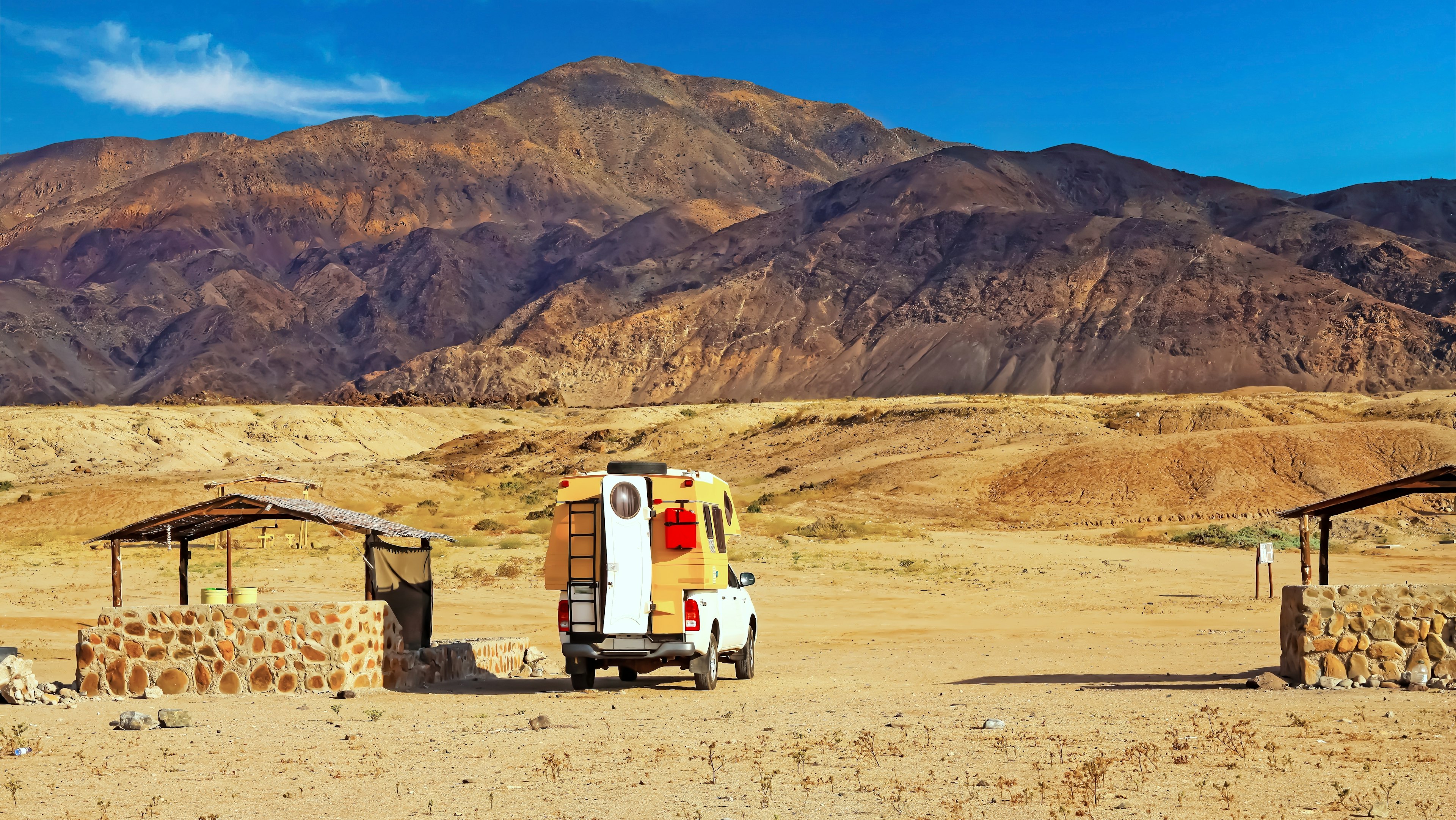 A camper can sits in the orange desert looking out at a mountain. Atacama, Chile