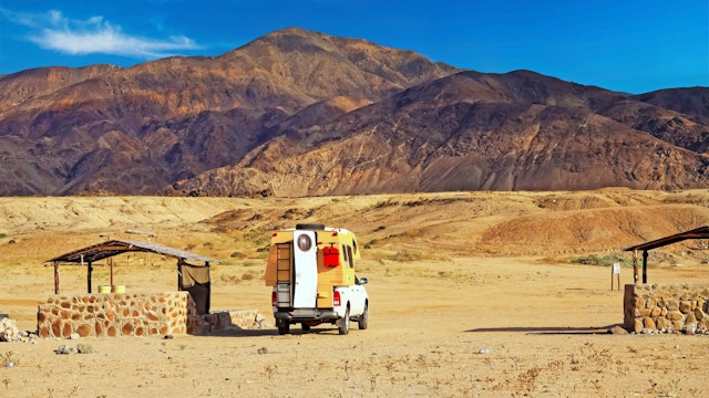 A camper can sits in the orange desert looking out at a mountain. Atacama, Chile