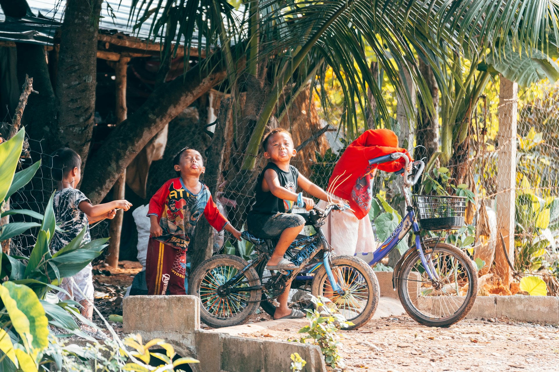 Children on bicycles make faces at the camera in the village of Vang Vieng, Laos