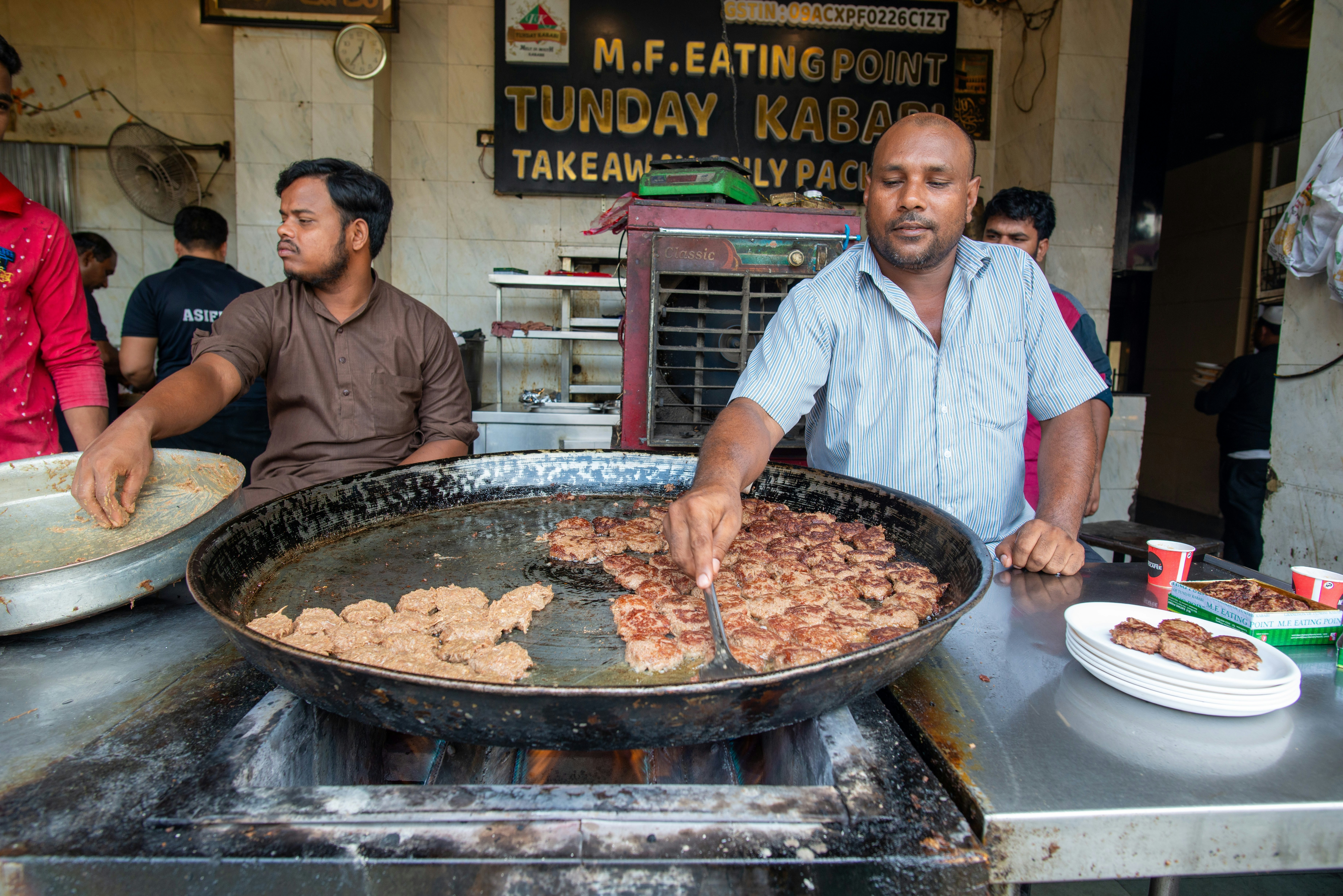 Men fry kebabs in traditional pan, at the Tunday Ke Kabab shop in Lucknow.