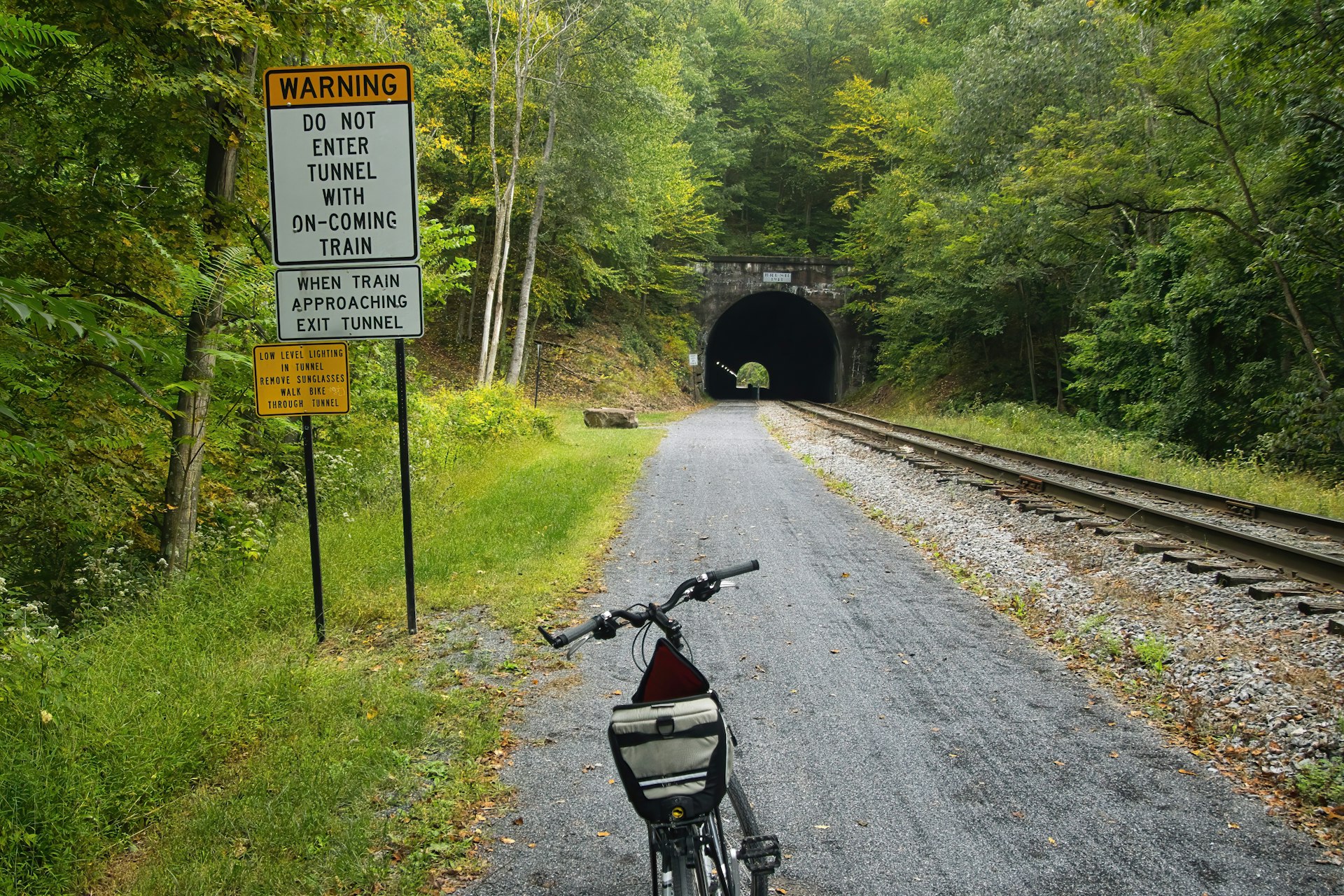 Landscape of a bike parked near a warning sign at the approach to a tunnel on the Great Allegheny Passage recreational trail, Pennsylvania