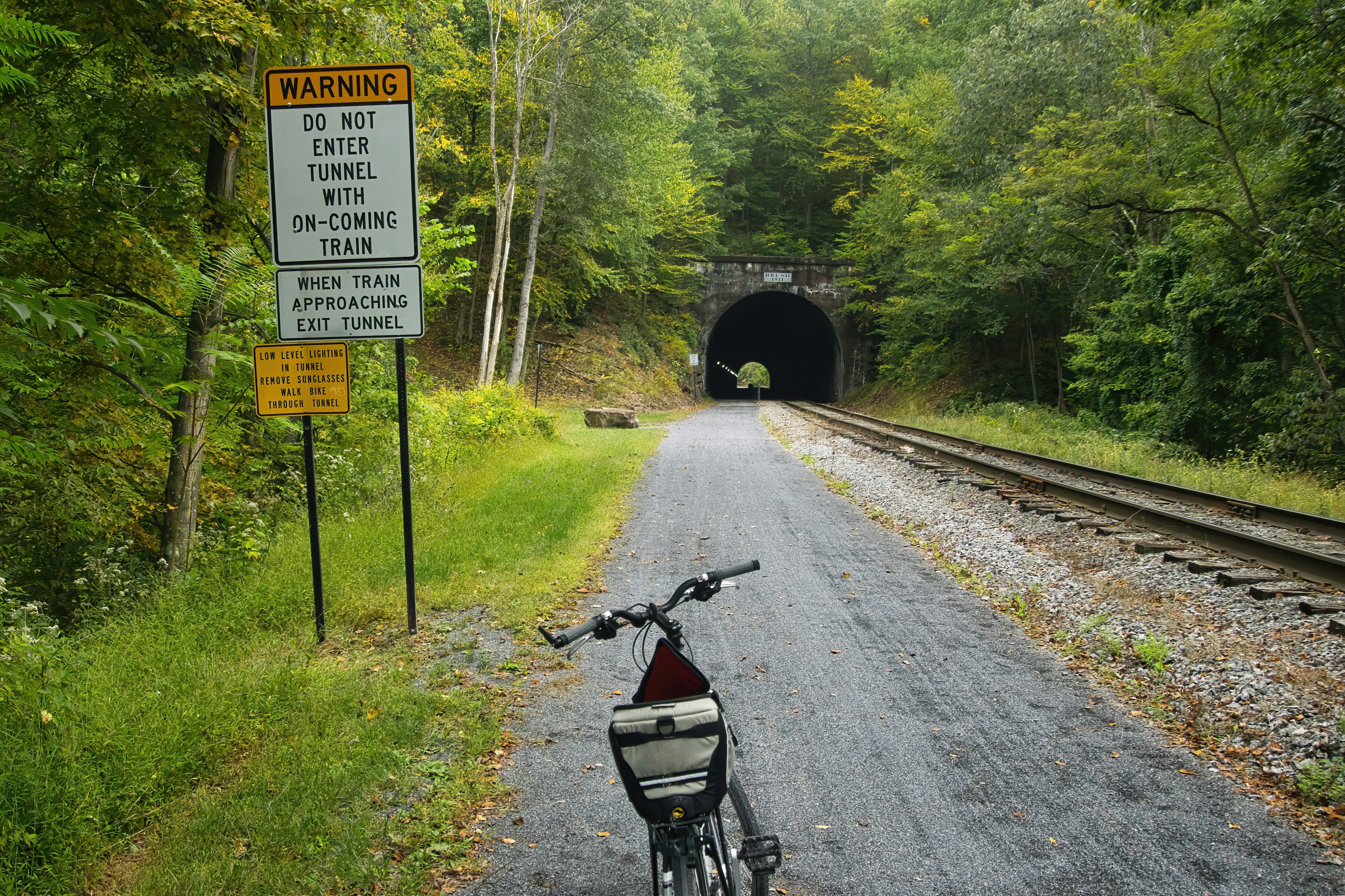 Landscape of a bike parked near a warning sign at the approach to a tunnel on the Great Allegheny Passage recreational trail, Pennsylvania