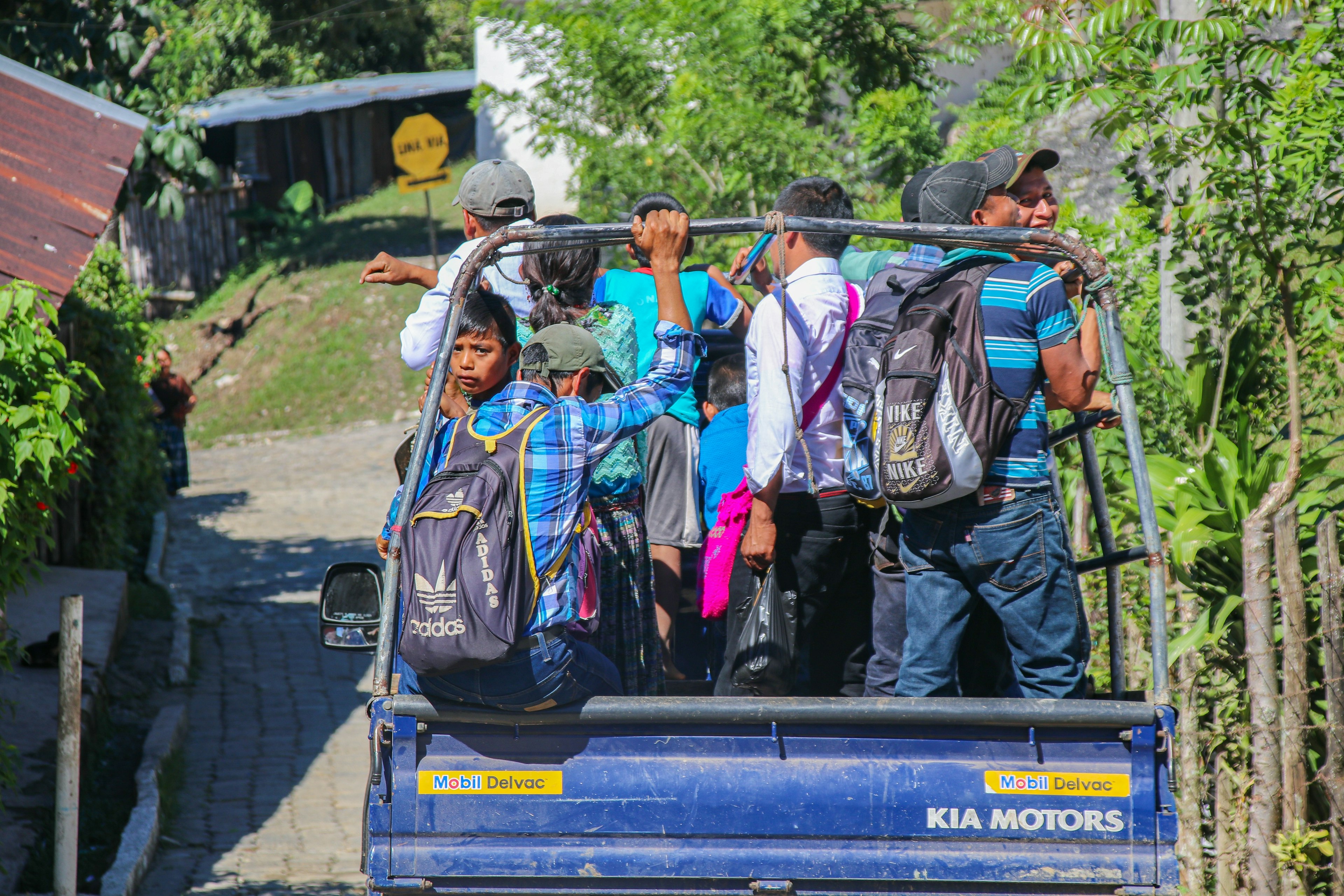 A group of people standing in the flatbed of a pickup truck on the road in Guatemala