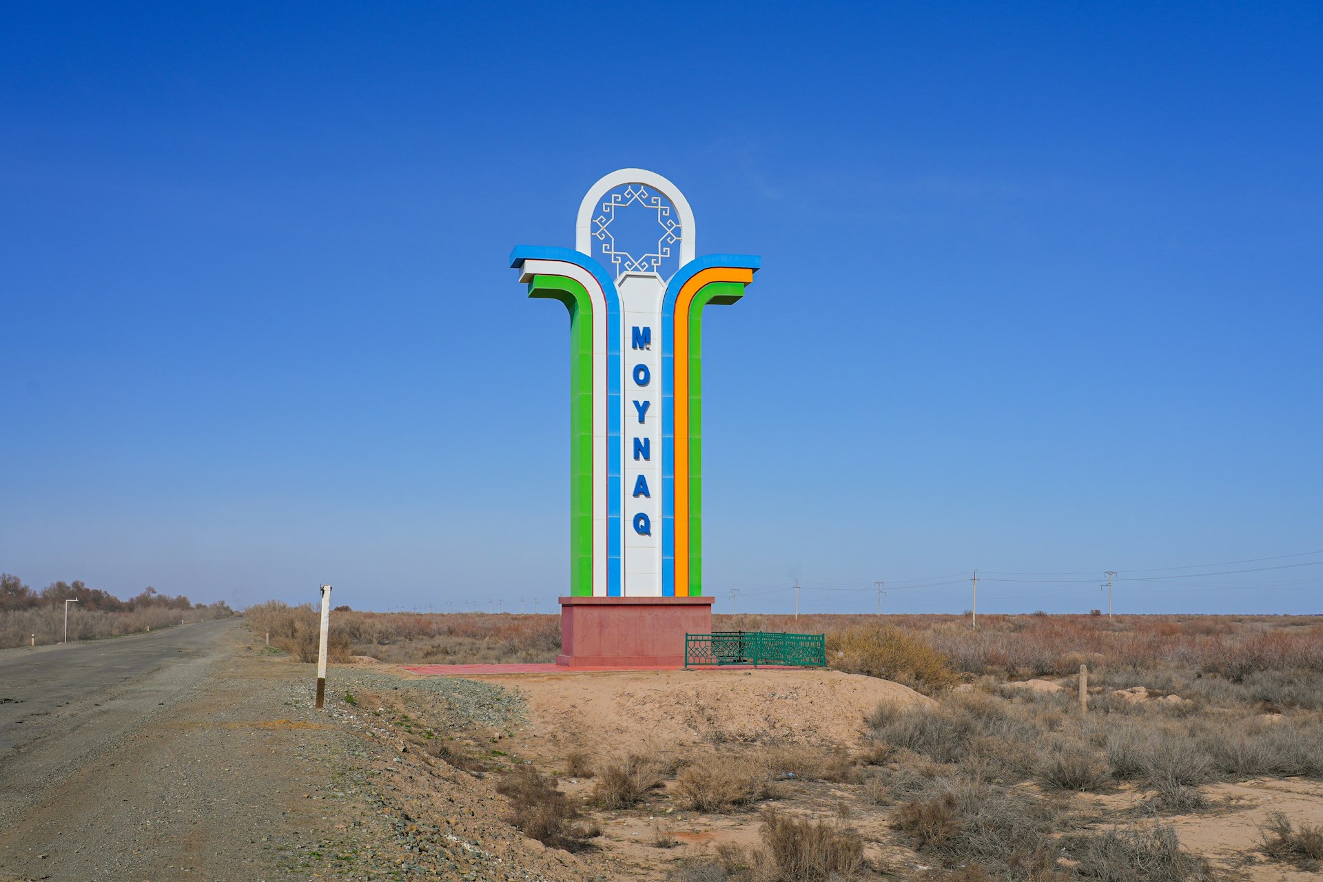 Large roadside landmark welcoming drivers to Moynaq (Muynak) featuring the colours of the Uzbek flag in Karakalpakstan, in western Uzbekistan