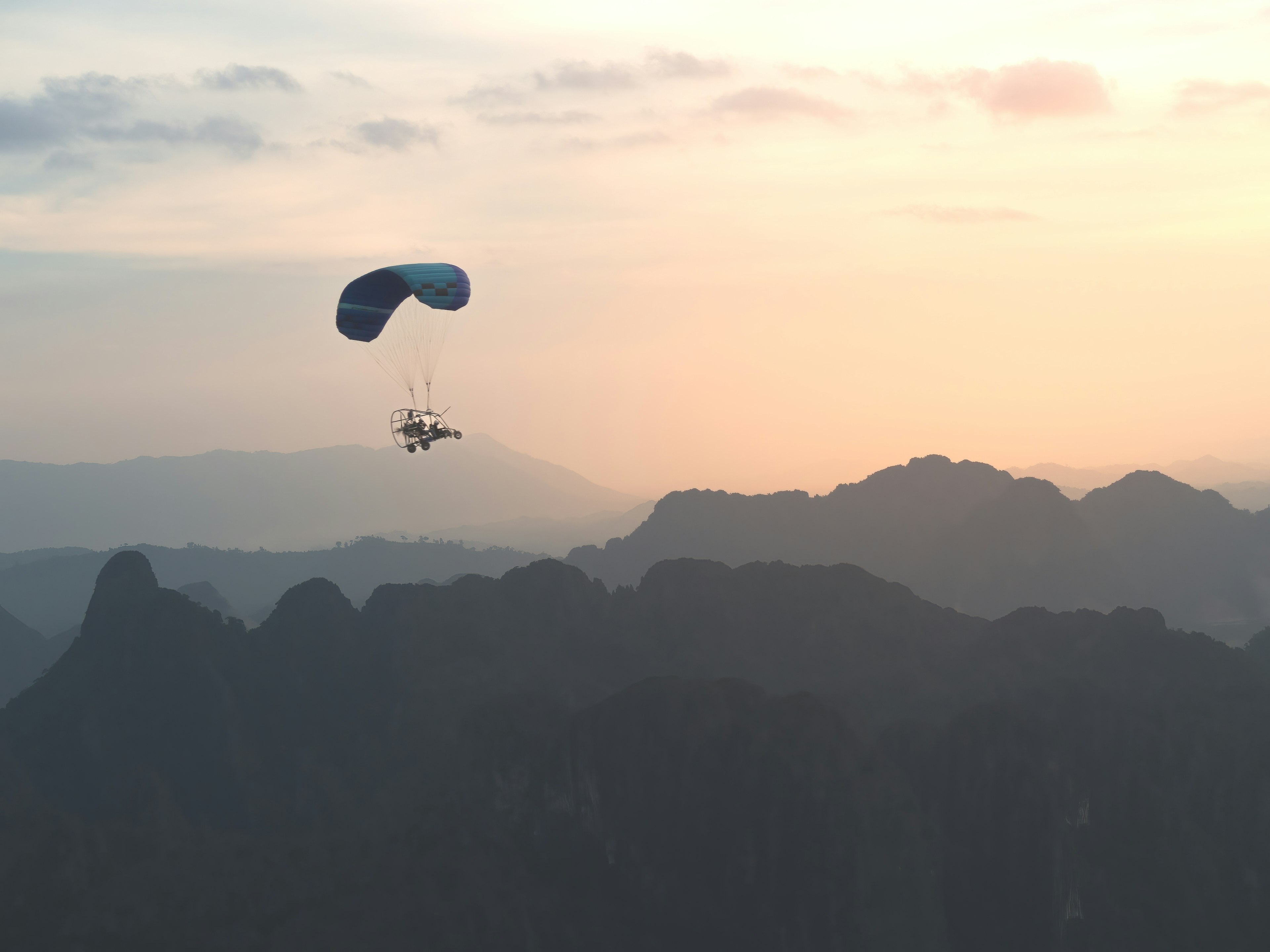 Tourists paramotoring over a valley at dawn in Vang Vieng, Laos