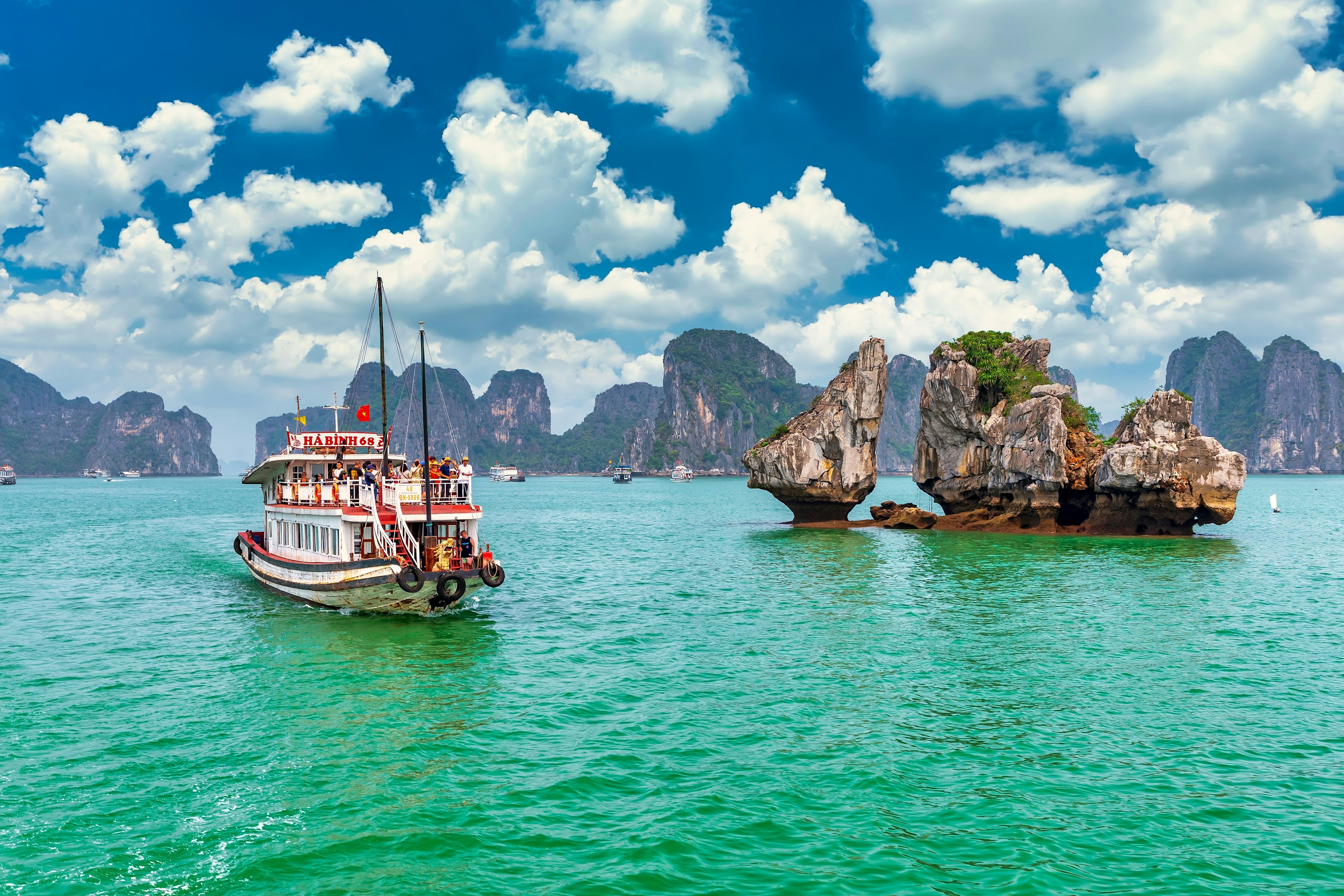 A boat floats by islands in Halong Bay, Vietnam