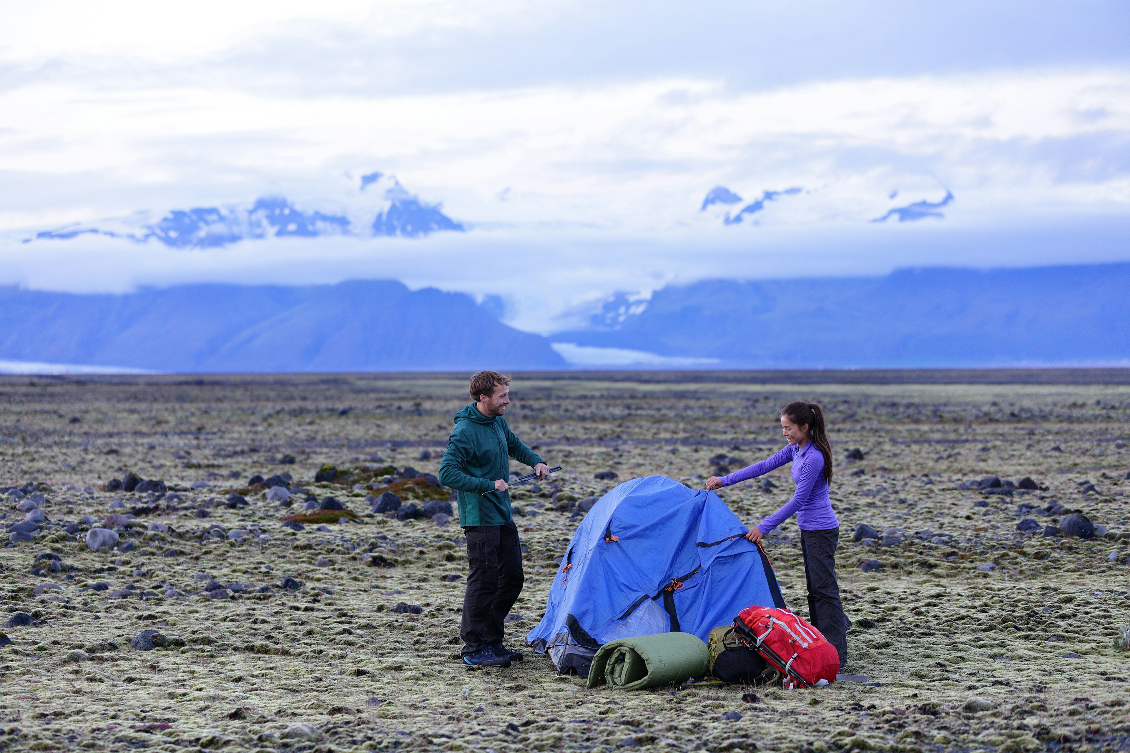 Camping couple pitching a tent after hiking in Iceland's back country