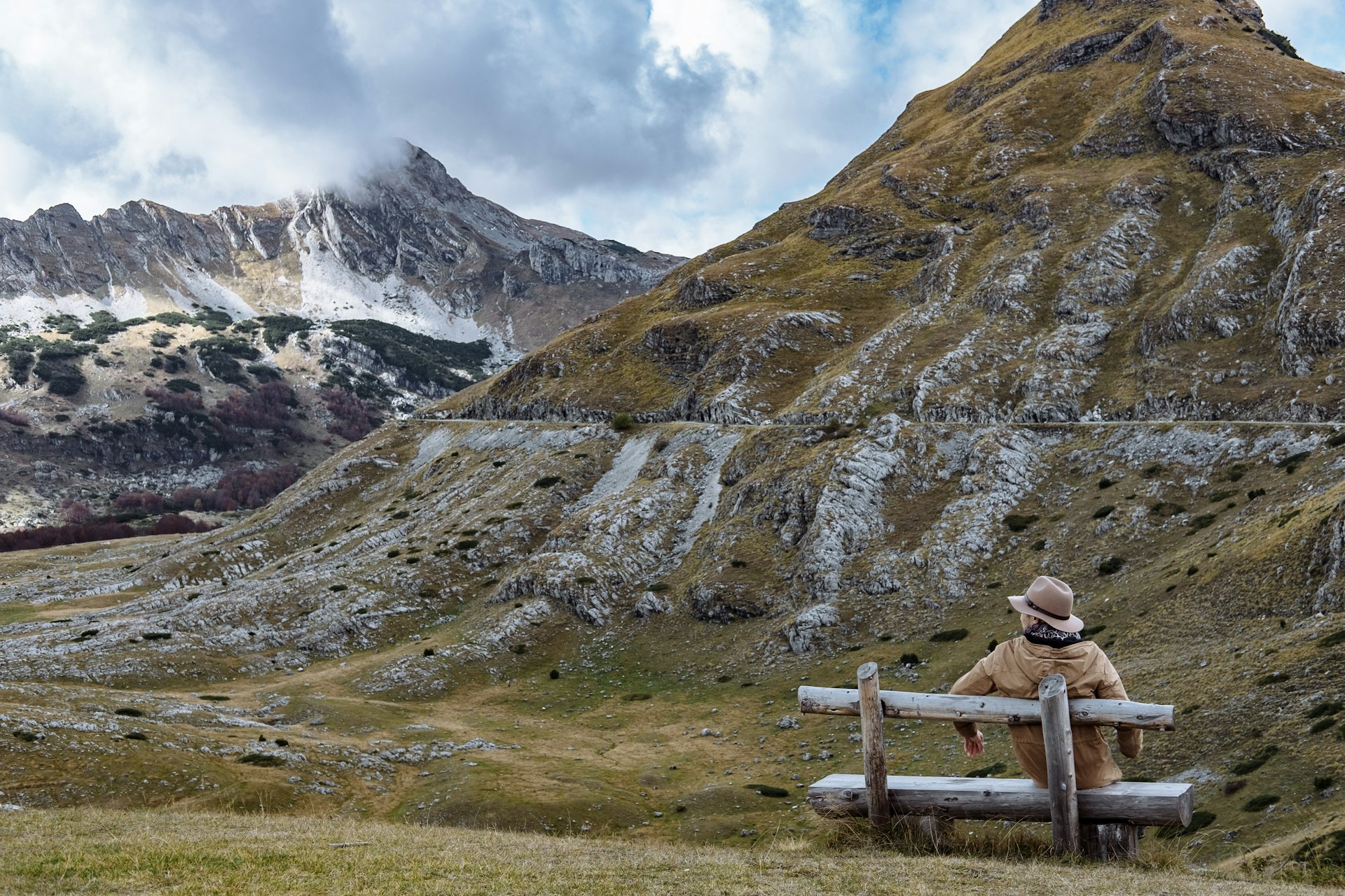 A solo hiker sits on a bench enjoying autumn in the mountains of Durmitor, Montenegro