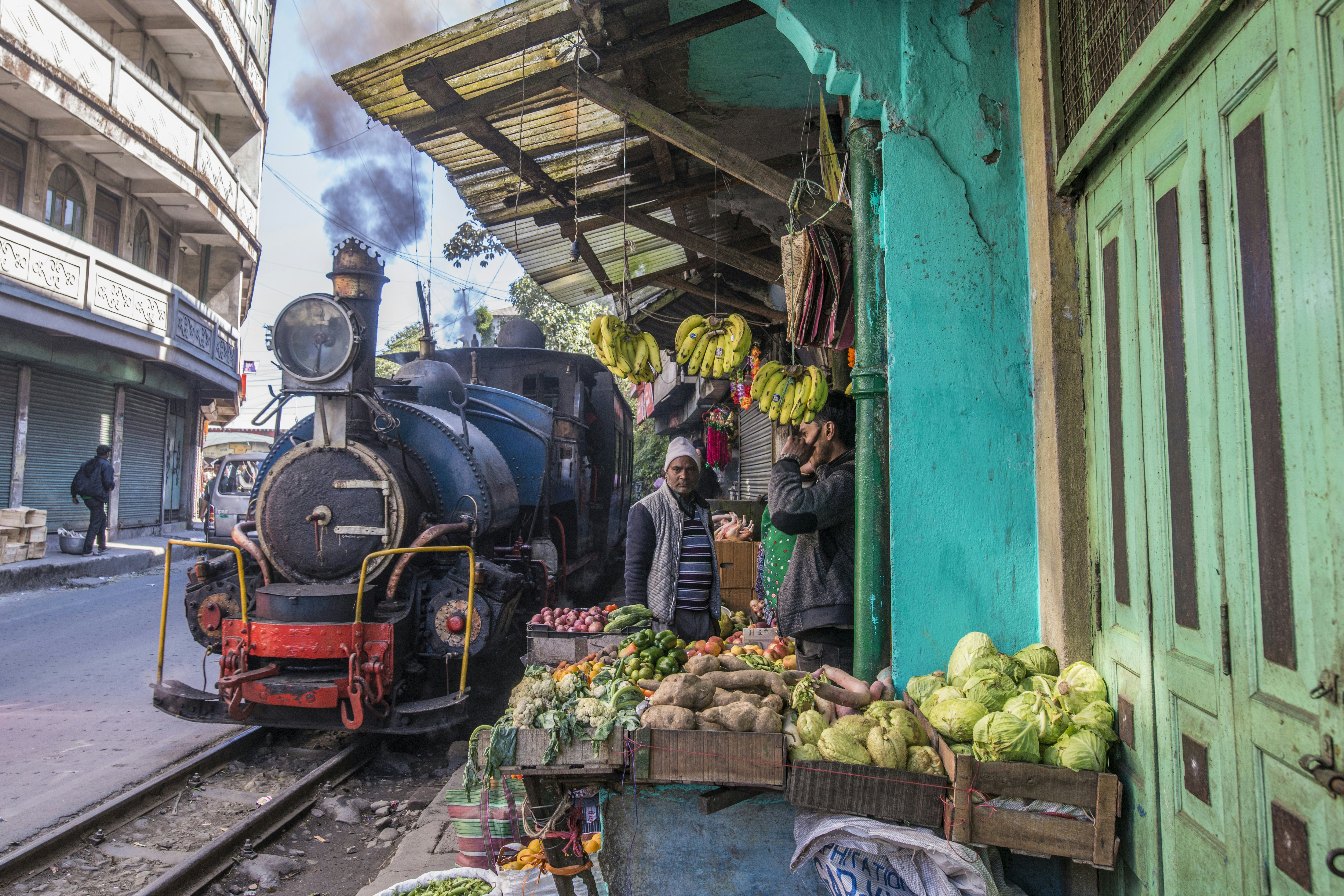 The Darjeeling Himalayan Railway passes by produce venders in the town of Ghum, West Bengal, India