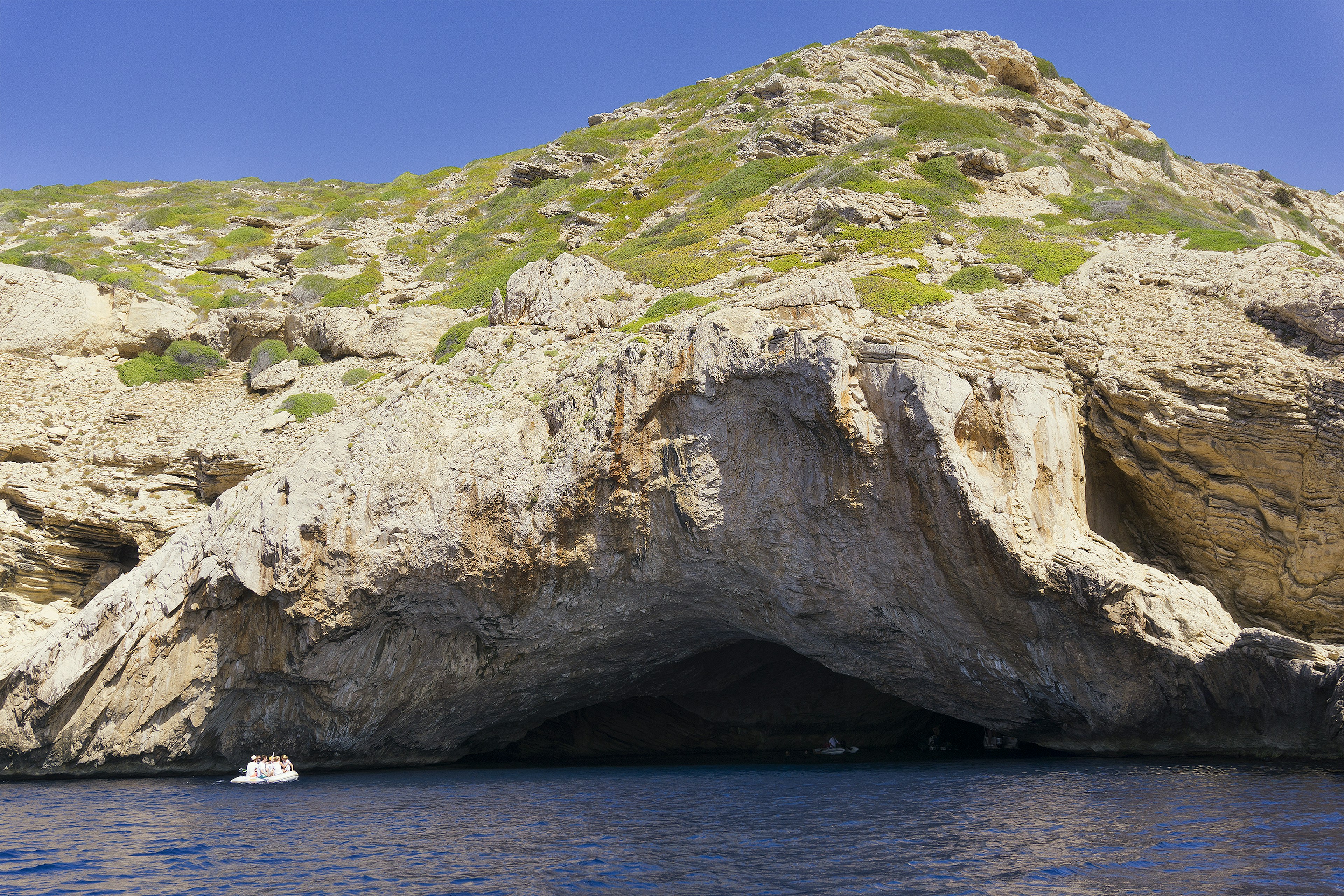 A small boat explores the picturesque coast of Cabrera Island