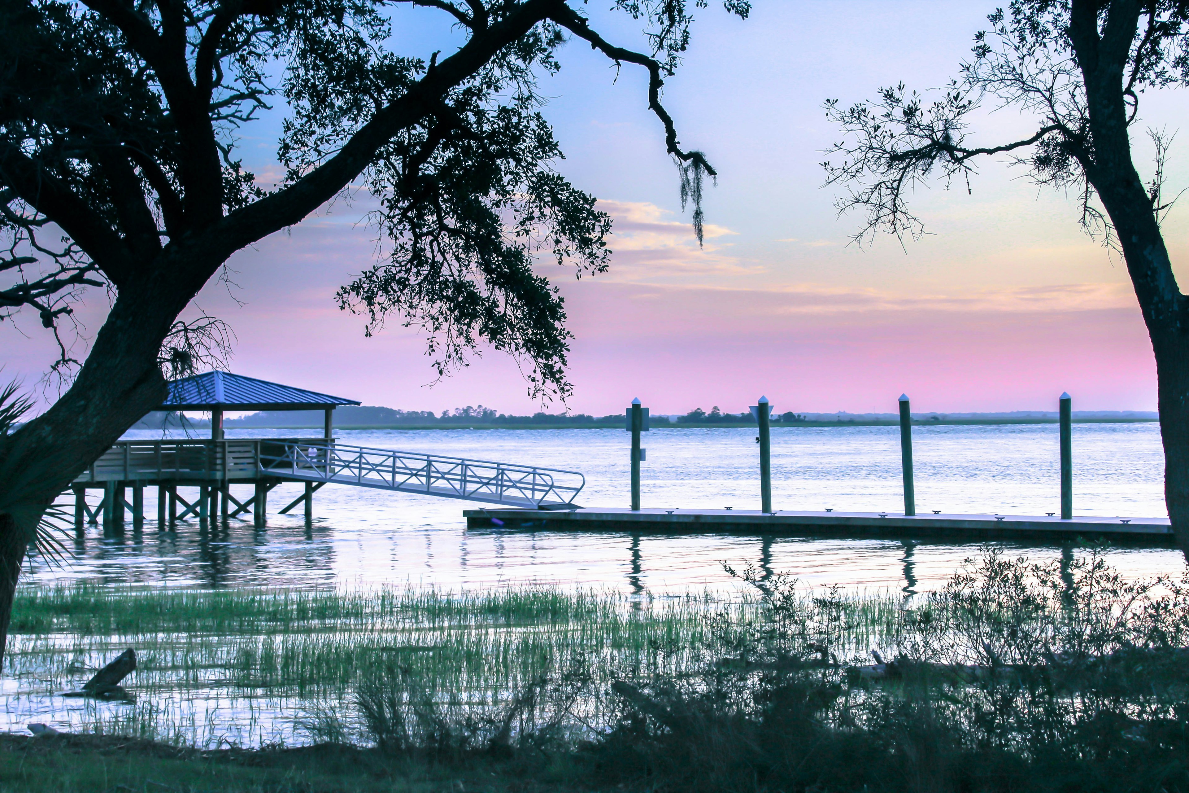 A pink sky as the sun sets over a waterway with a small dock