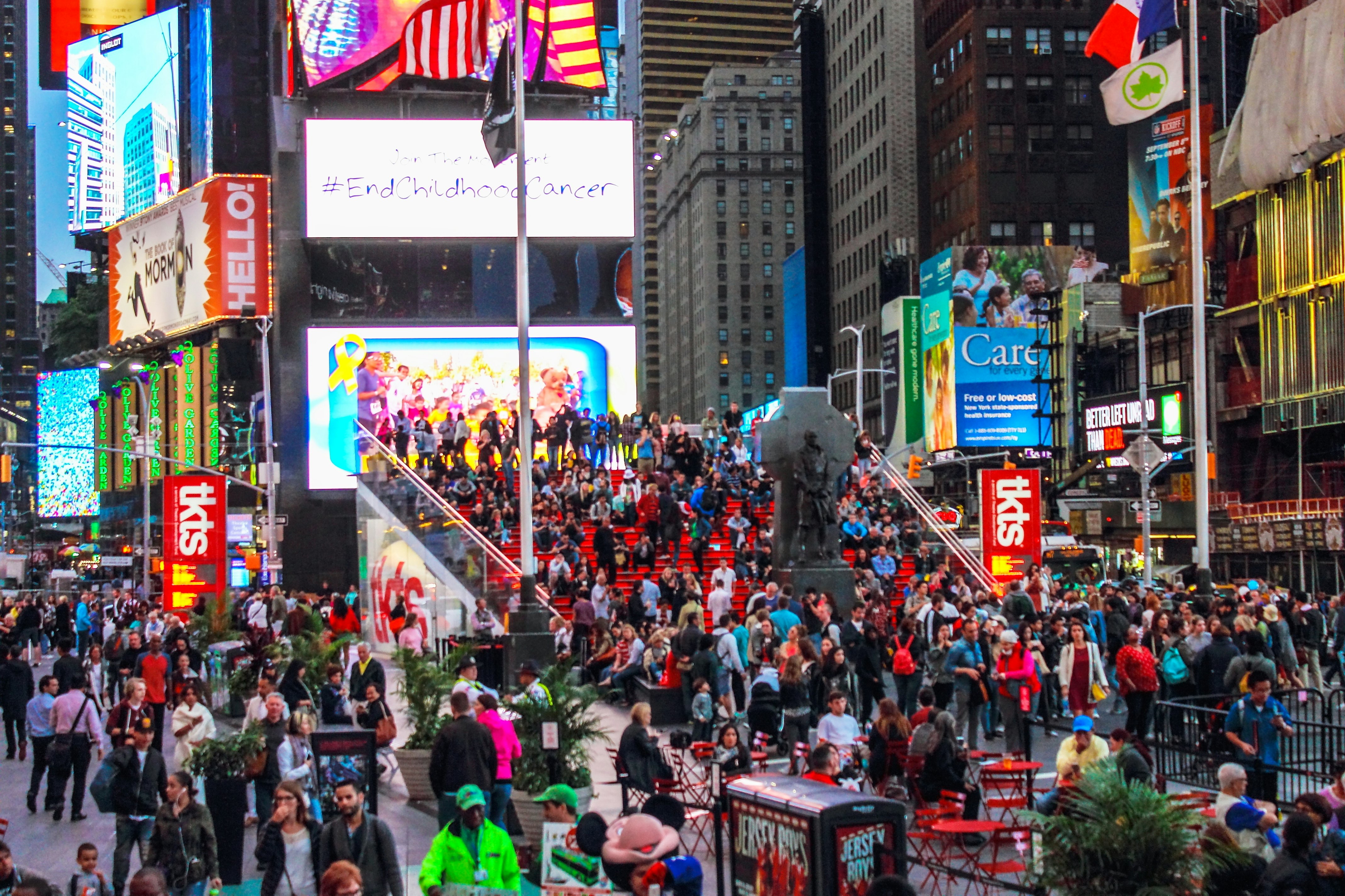 Crowds of people gather in and around the red steps of the TKTS booth in Times Square