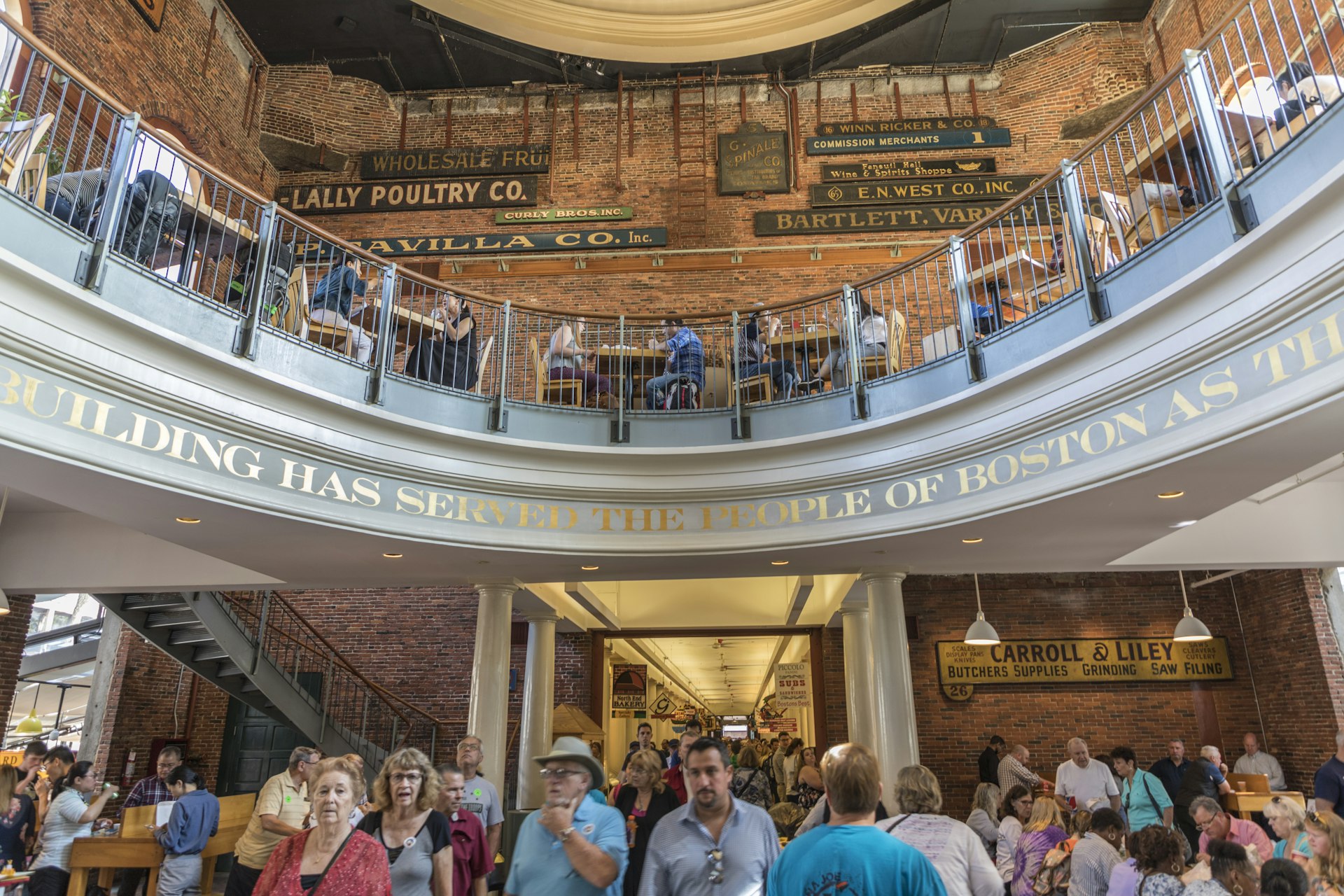 A busy indoor market place with many people moving through it