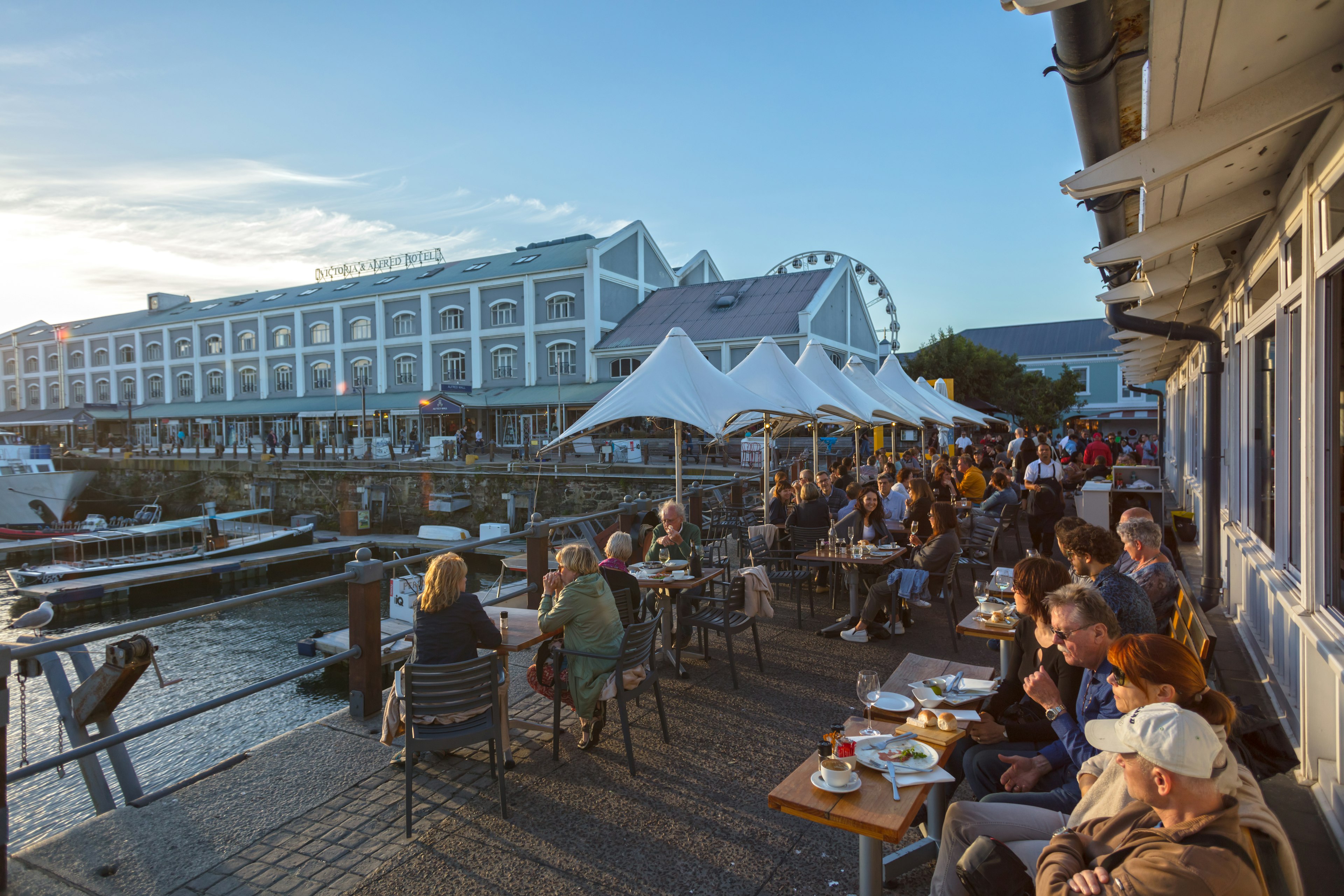 People enjoy sunset on a restaurant patio overlooking the waterfront in Cape Town, South Africa