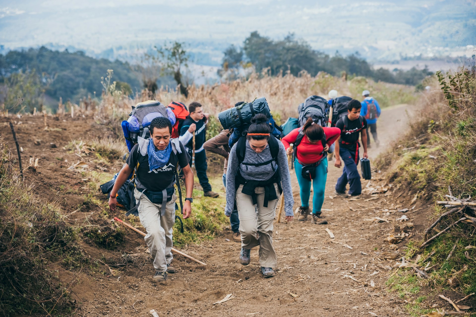 A group of hikers with large backpacks ascends the lower slopes of Acatenango Volcano, Guatemala