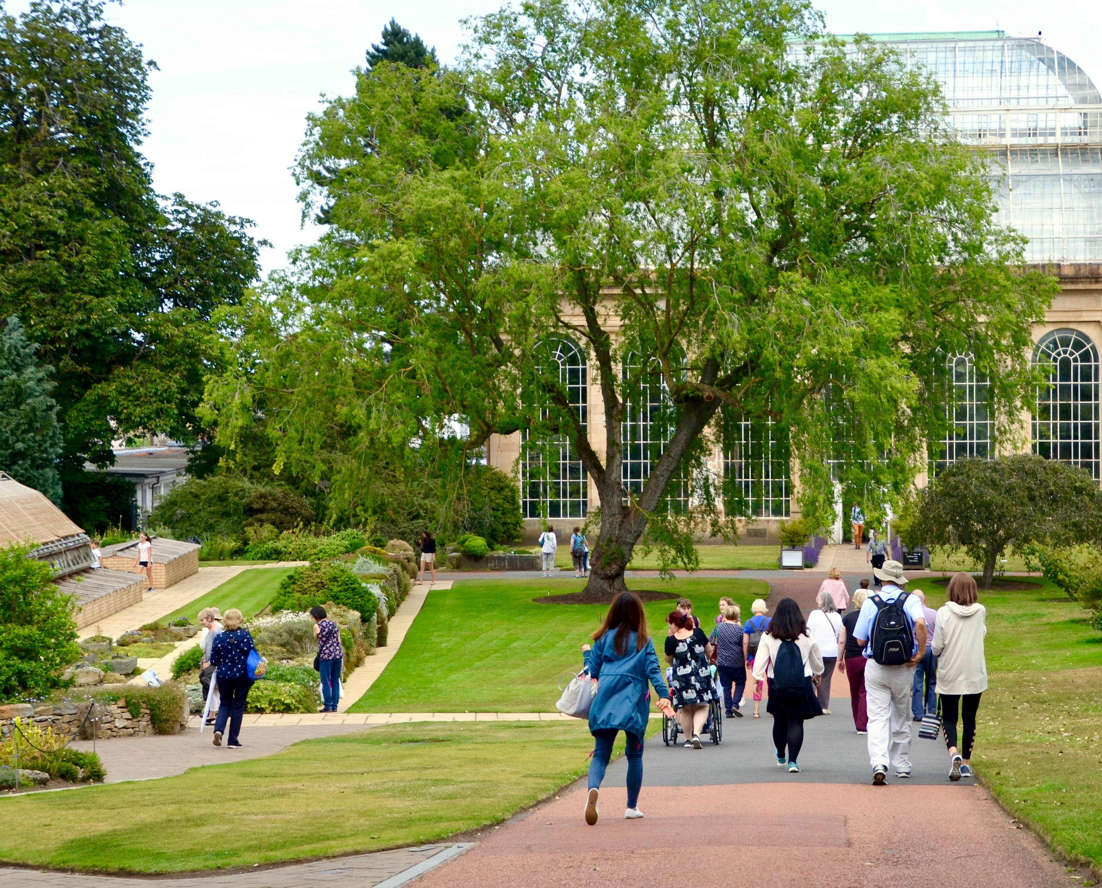 Visitors walking towards the Victorian Palm House in the Royal Botanic Gardens in Edinburgh.