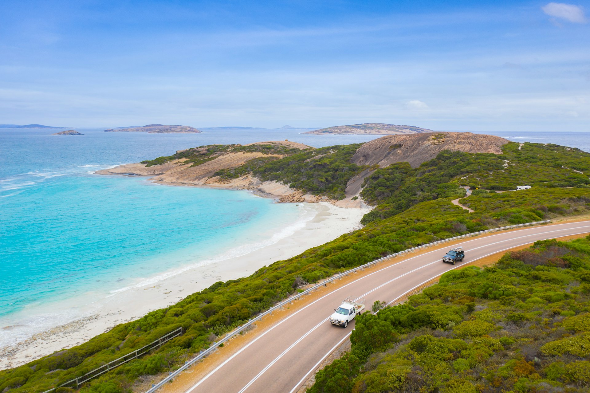 An aerial view of cars driving past the blue water and beaches on the Great Ocean Road, Victoria, Australia