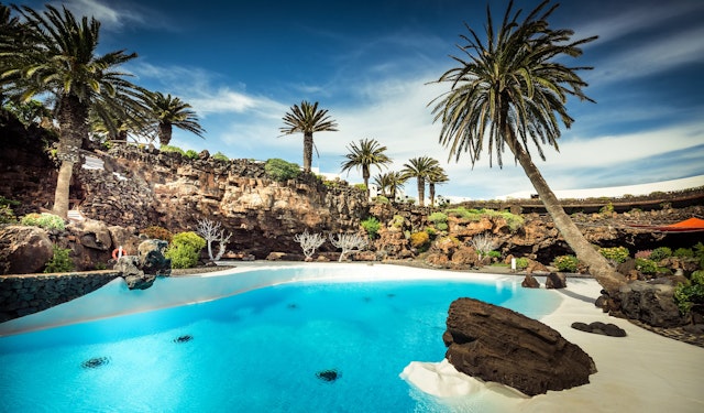 Jameos del Agua pool surrounded by rocks and palm trees in Lanzarote, Canary Islands, Spain