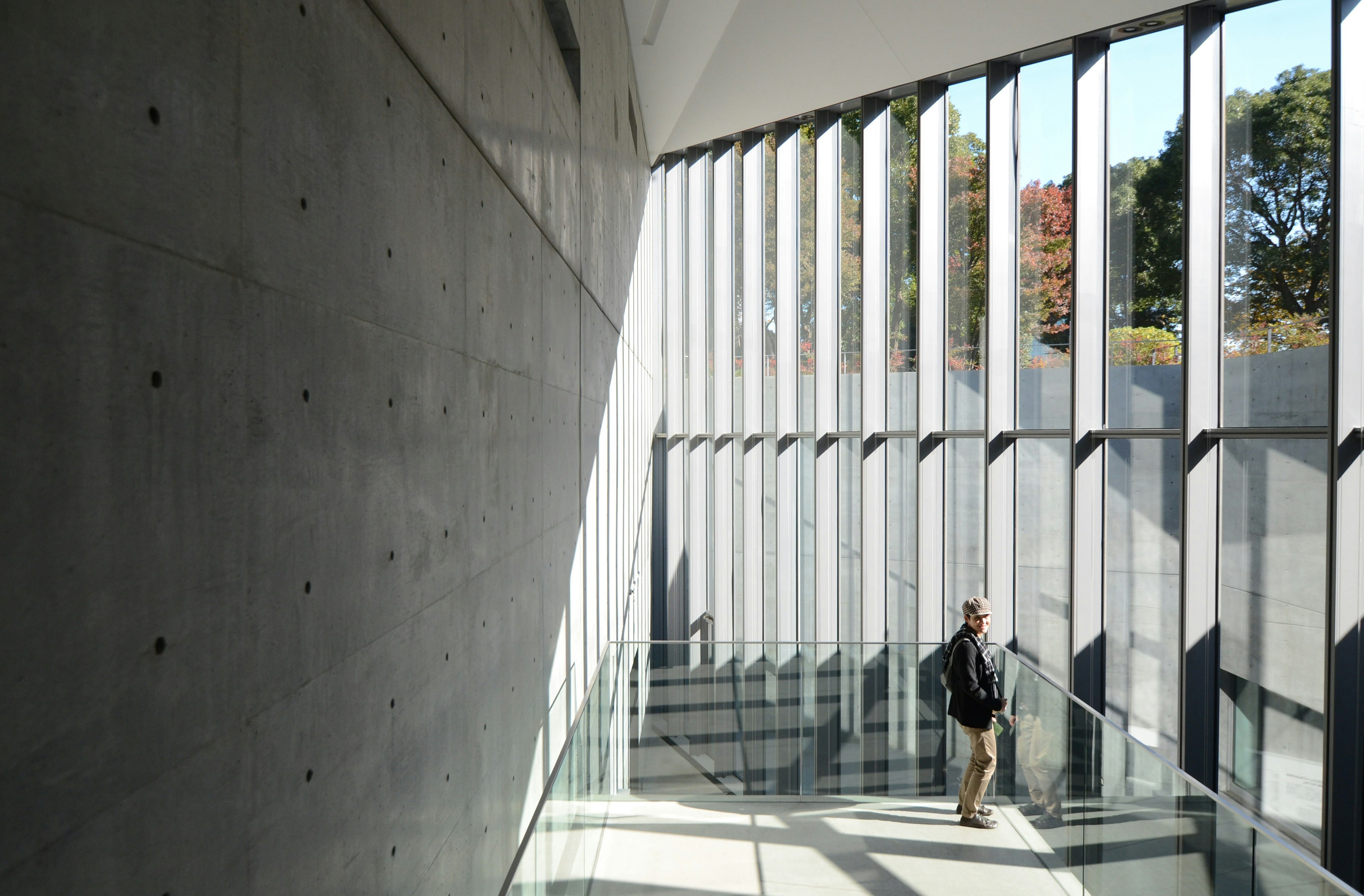 A man on a staircase with floor-to-ceiling windows inside the 21_21 Design Sight Museum in Roppongi