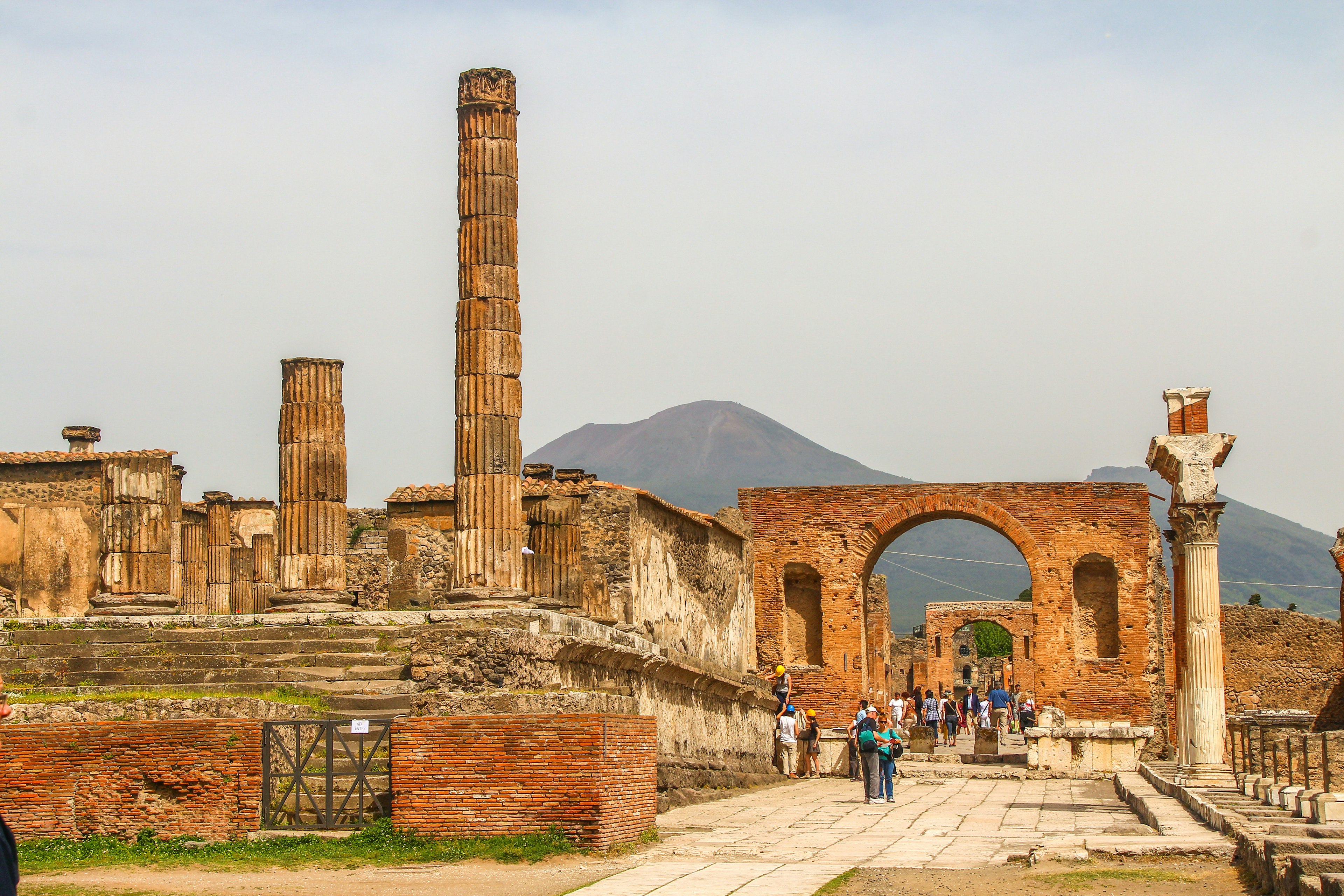 The ruined city of Pompeii. People walk around the ruins of the former city, which was destroyed by Mt Vesuvius. The volcano is visible in the background of the image.