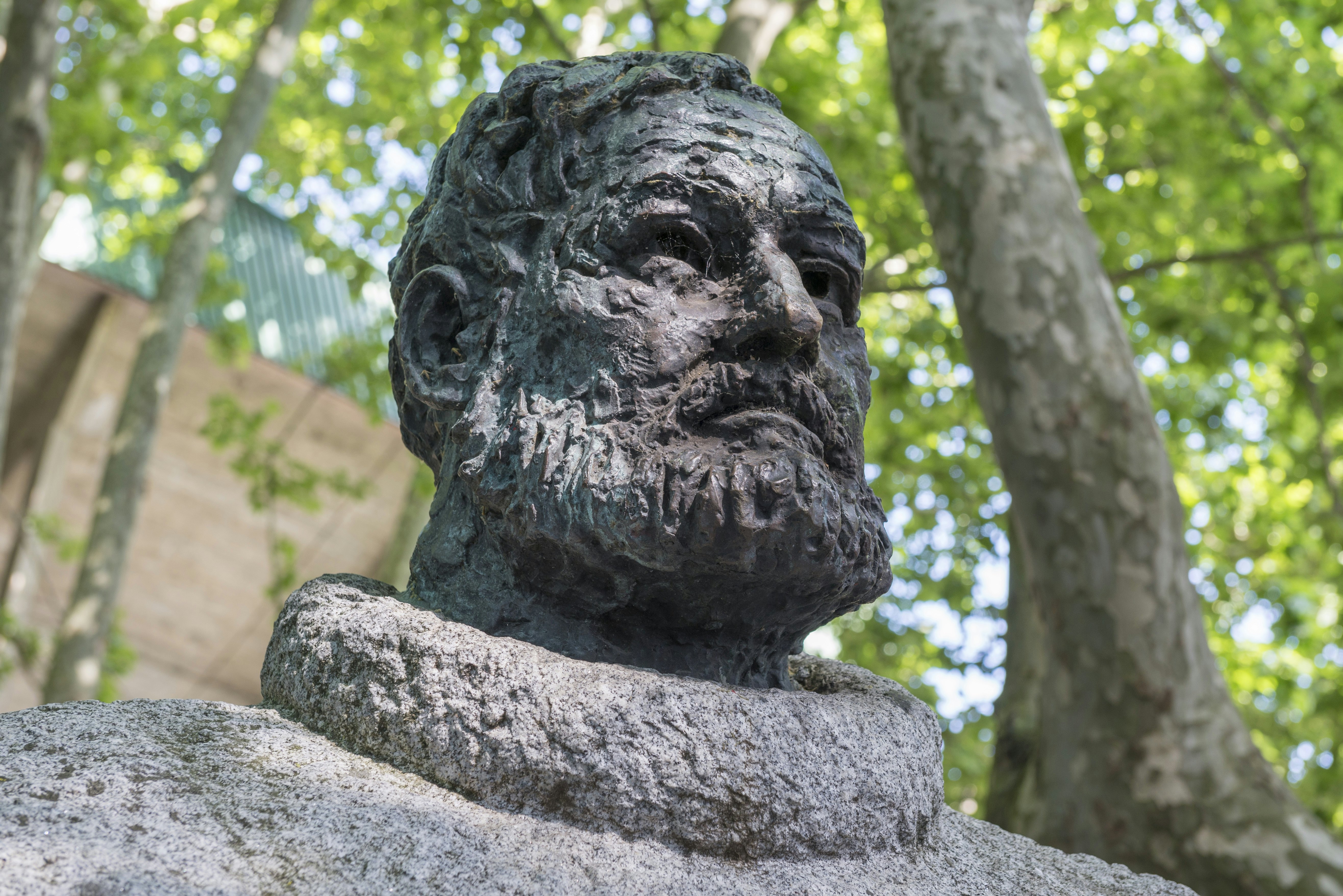 A statue of a bearded man under trees.