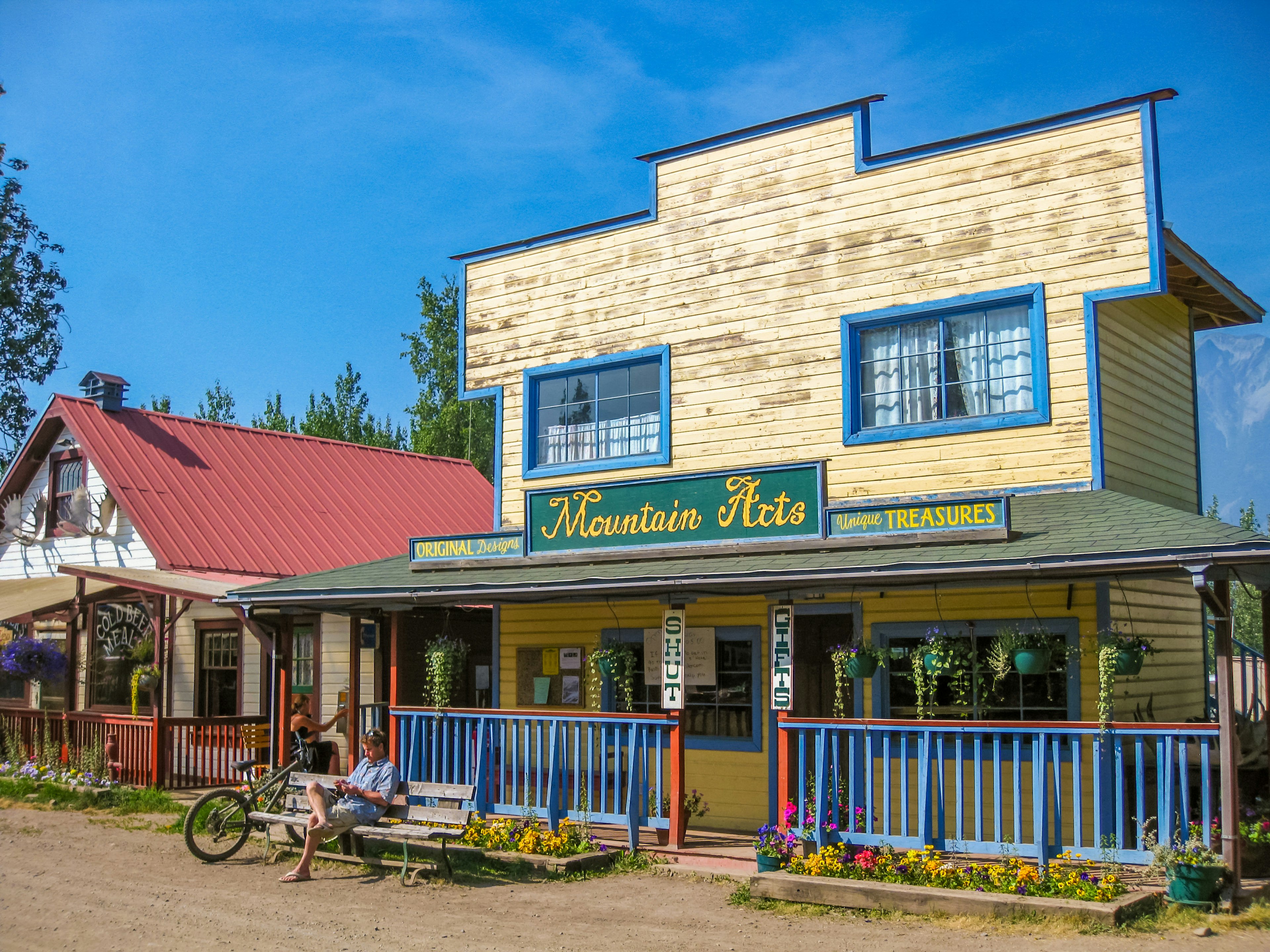 A person with a bike sits outside wooden-fronted store