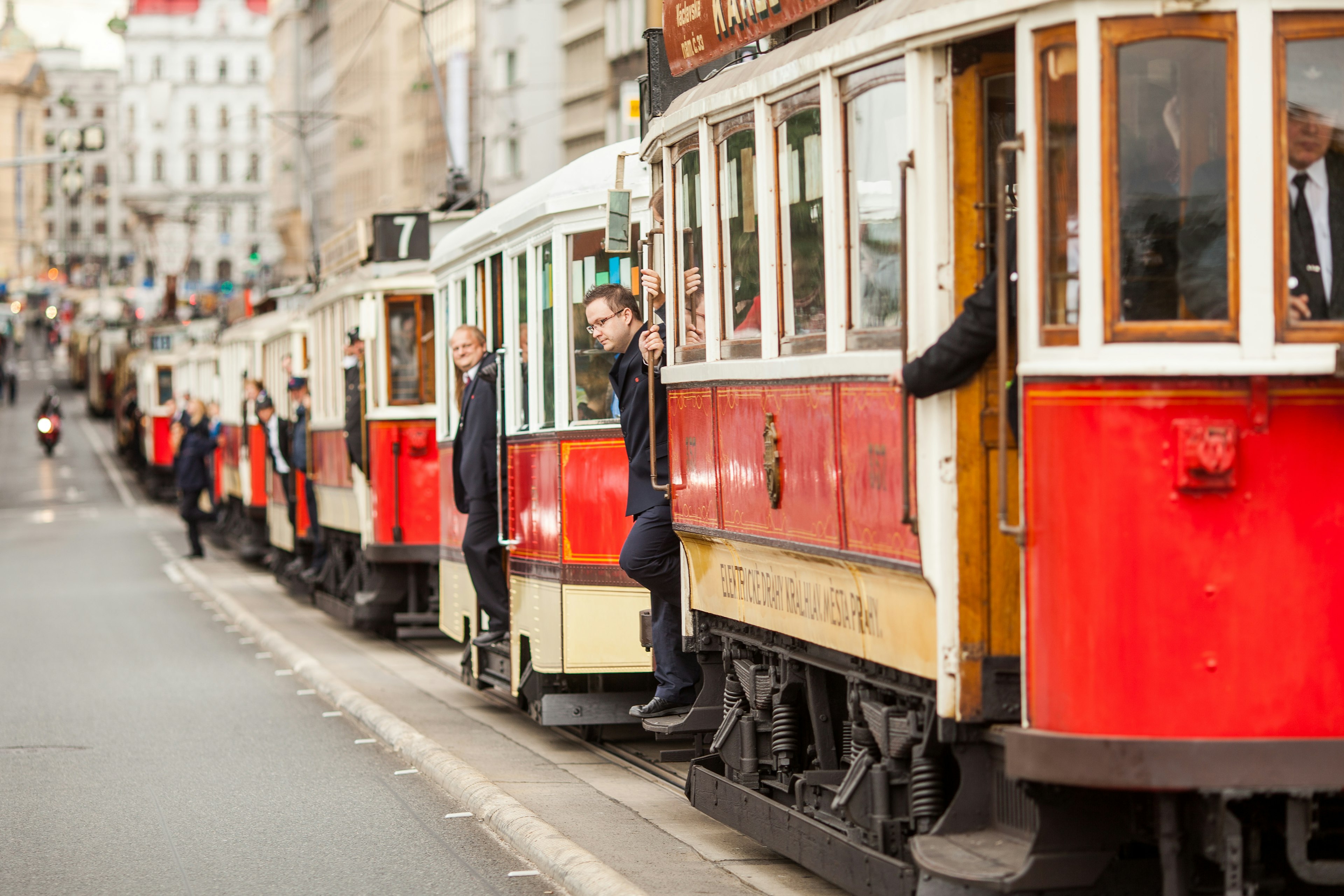 A parade of vintage red trams pass through the historic center of Prague