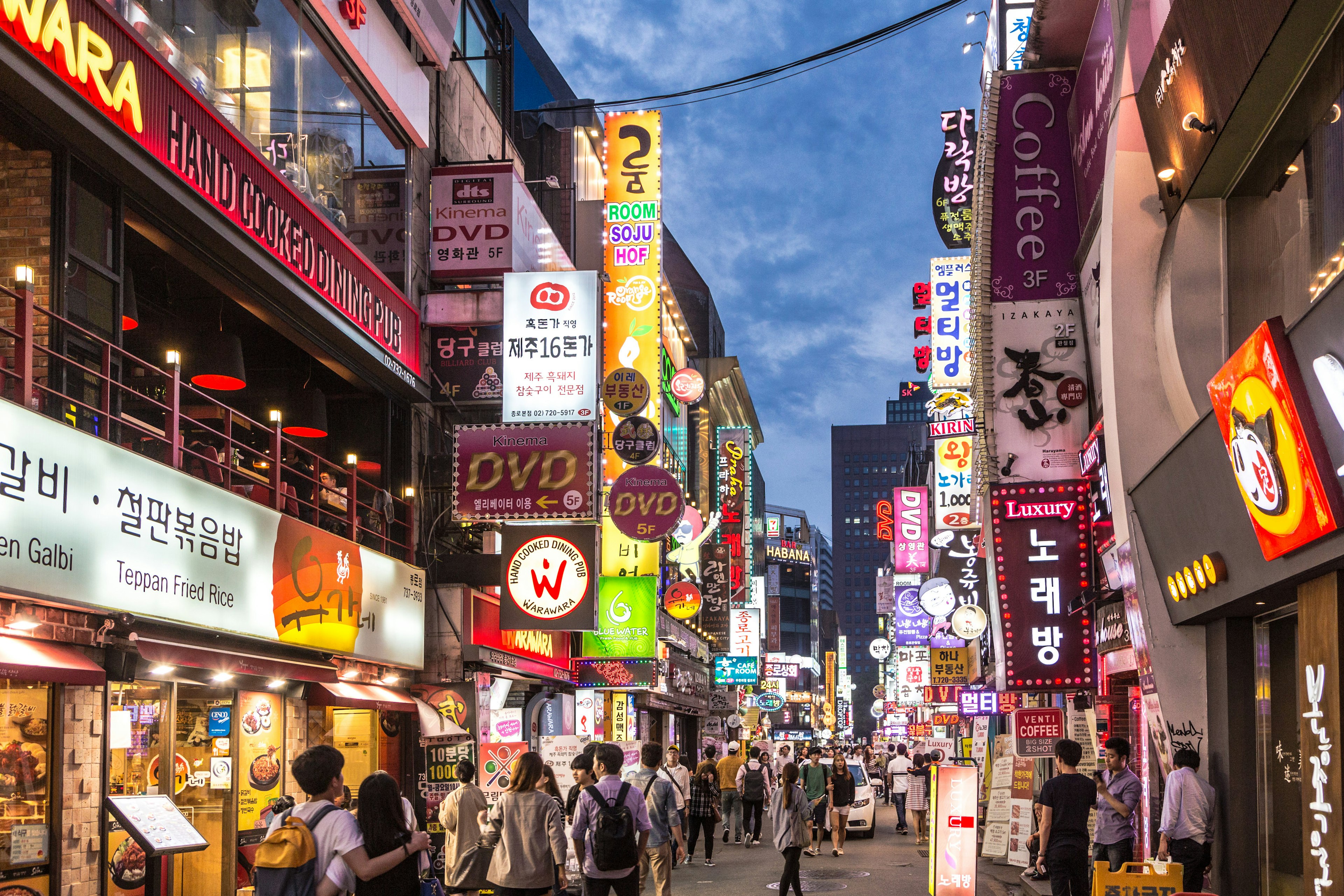 People wander in the walking street of the Myeong-dong shopping and entertainment district at night