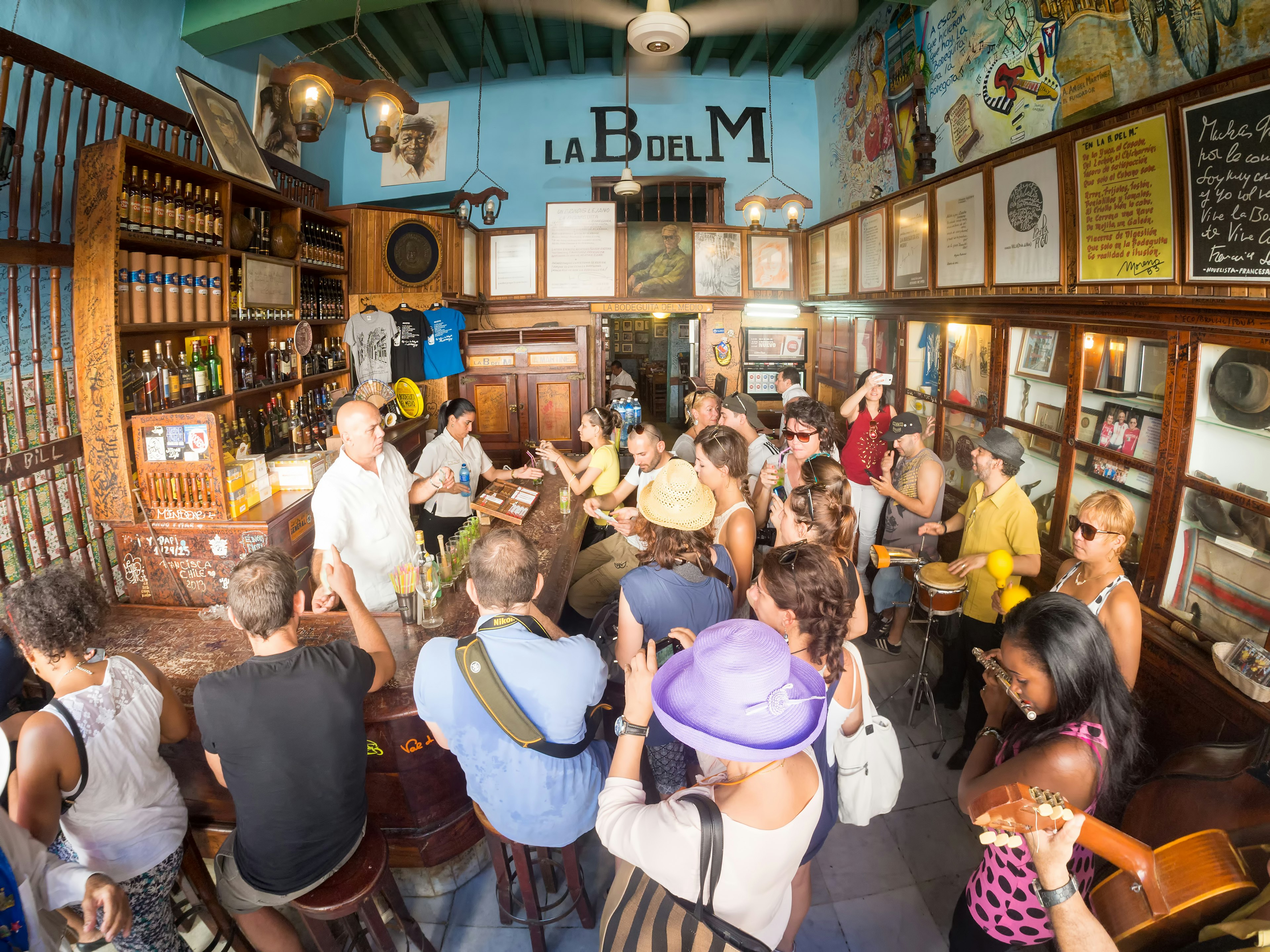 People crowd around a bar while musicians perform