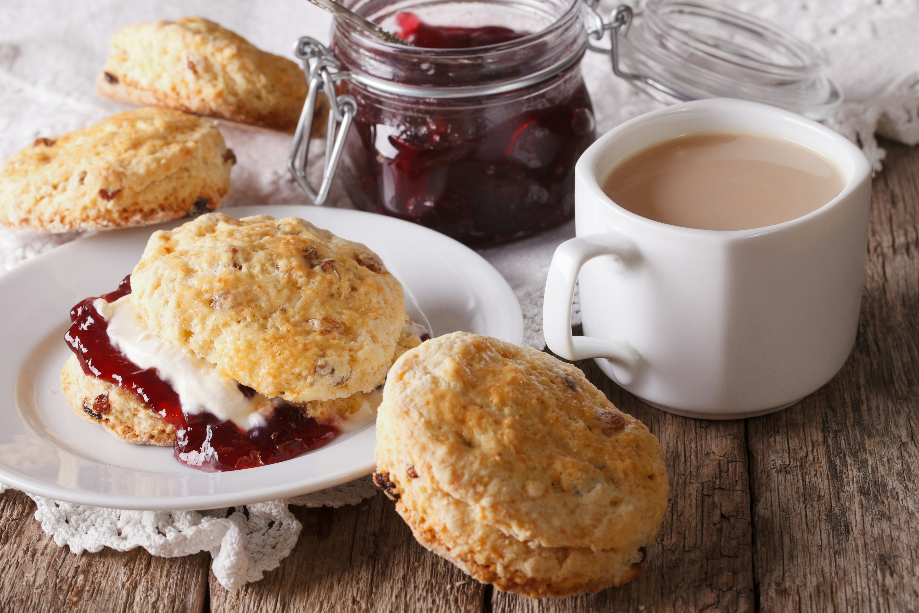 Scones with jam and tea with milk close-up on the table