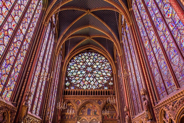 The colorful stained glass windows inside of a gothic French church.