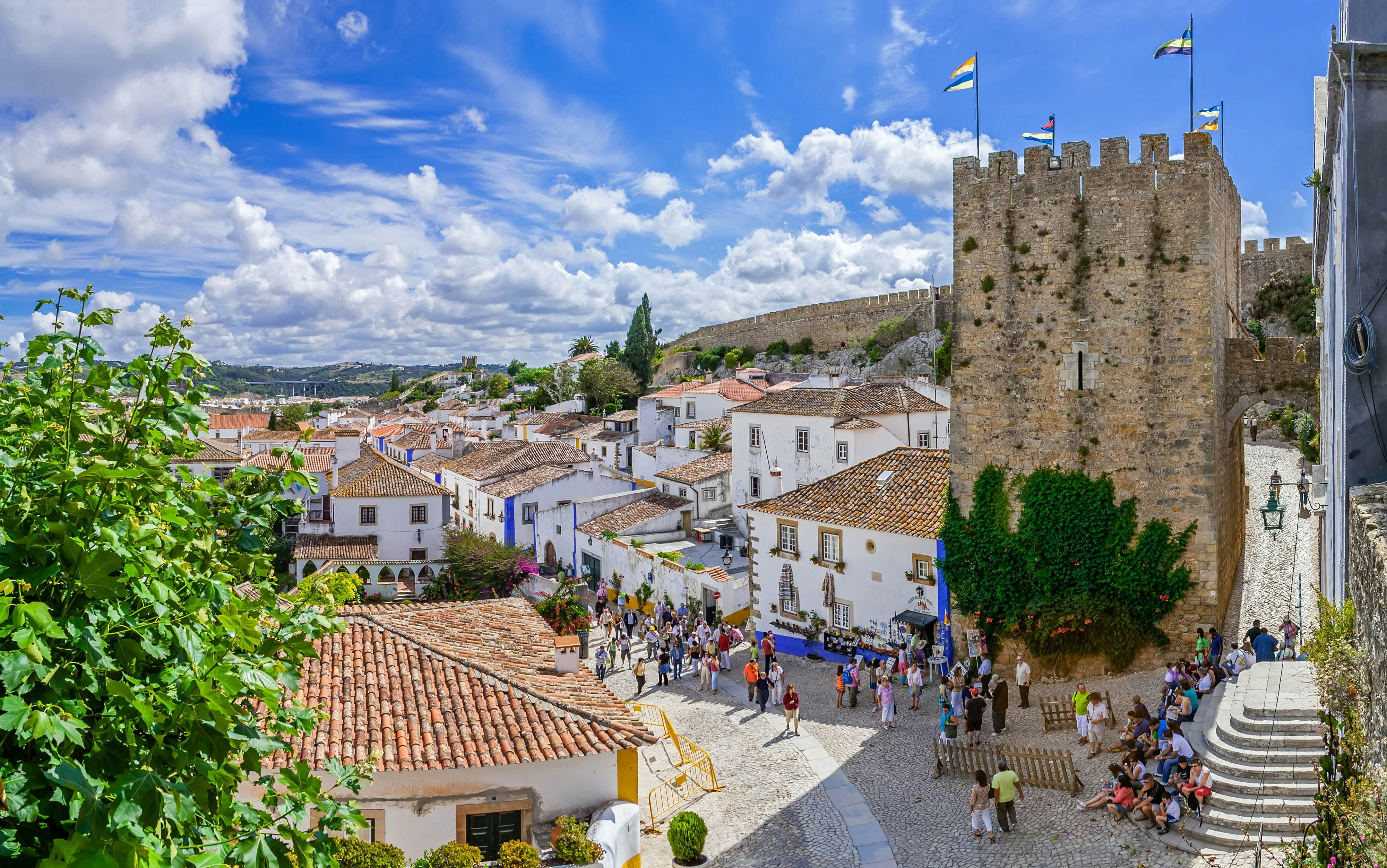 Tourists wander the cobbled streets of a medieval town center.