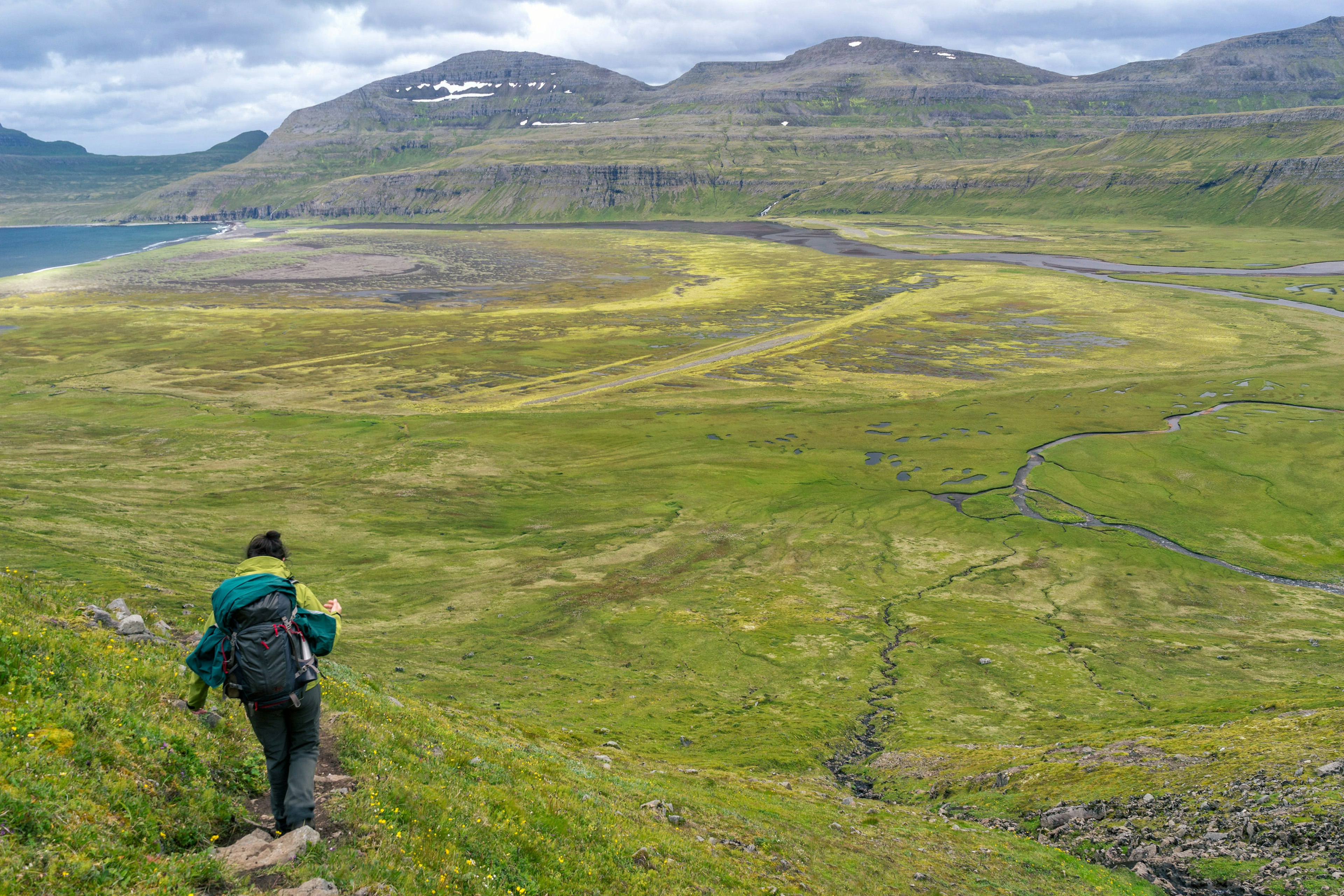 Woman hiking through grasslands in Hornstrandir National Park.