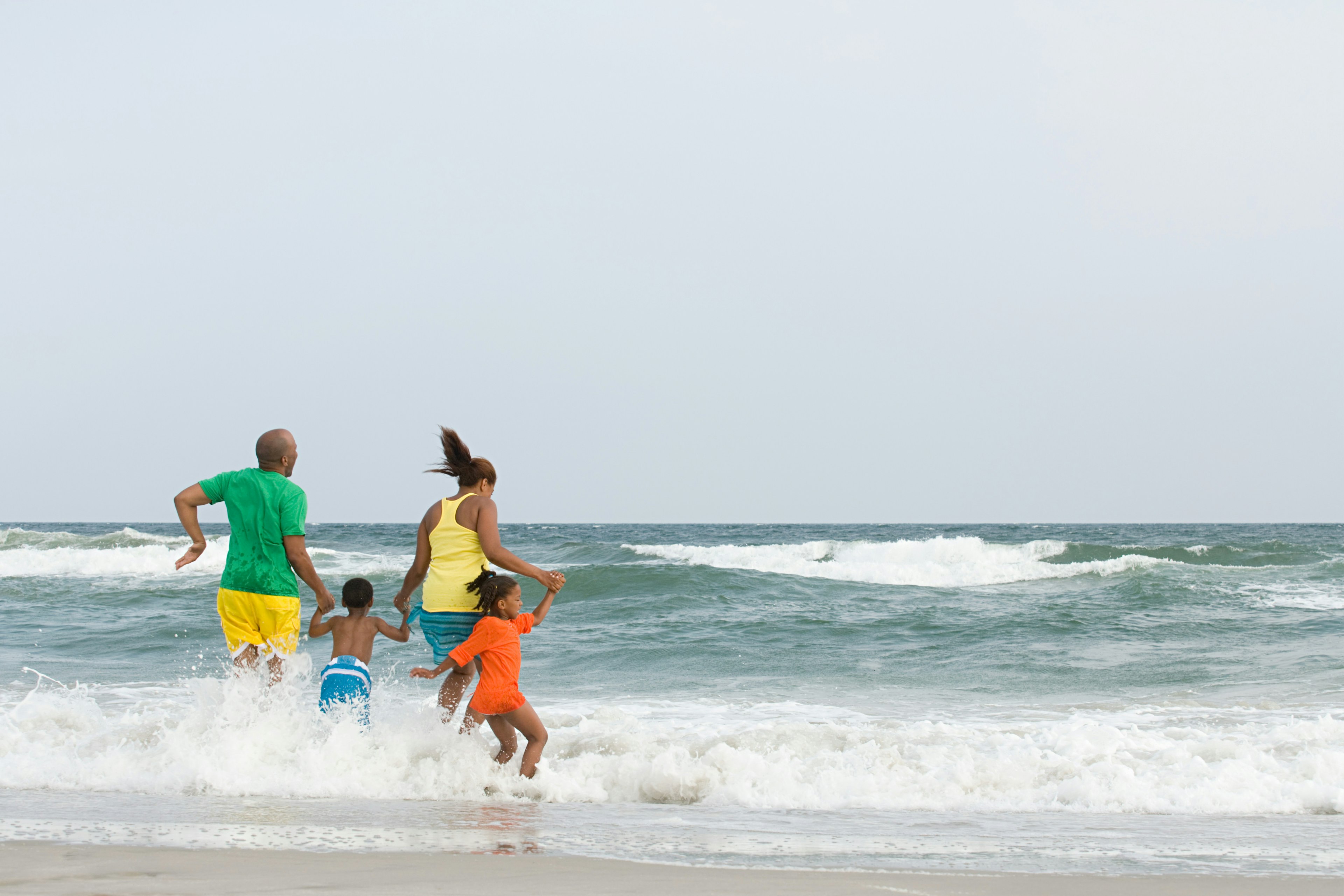 A Black family jumping over the waves off the shore of Montauk