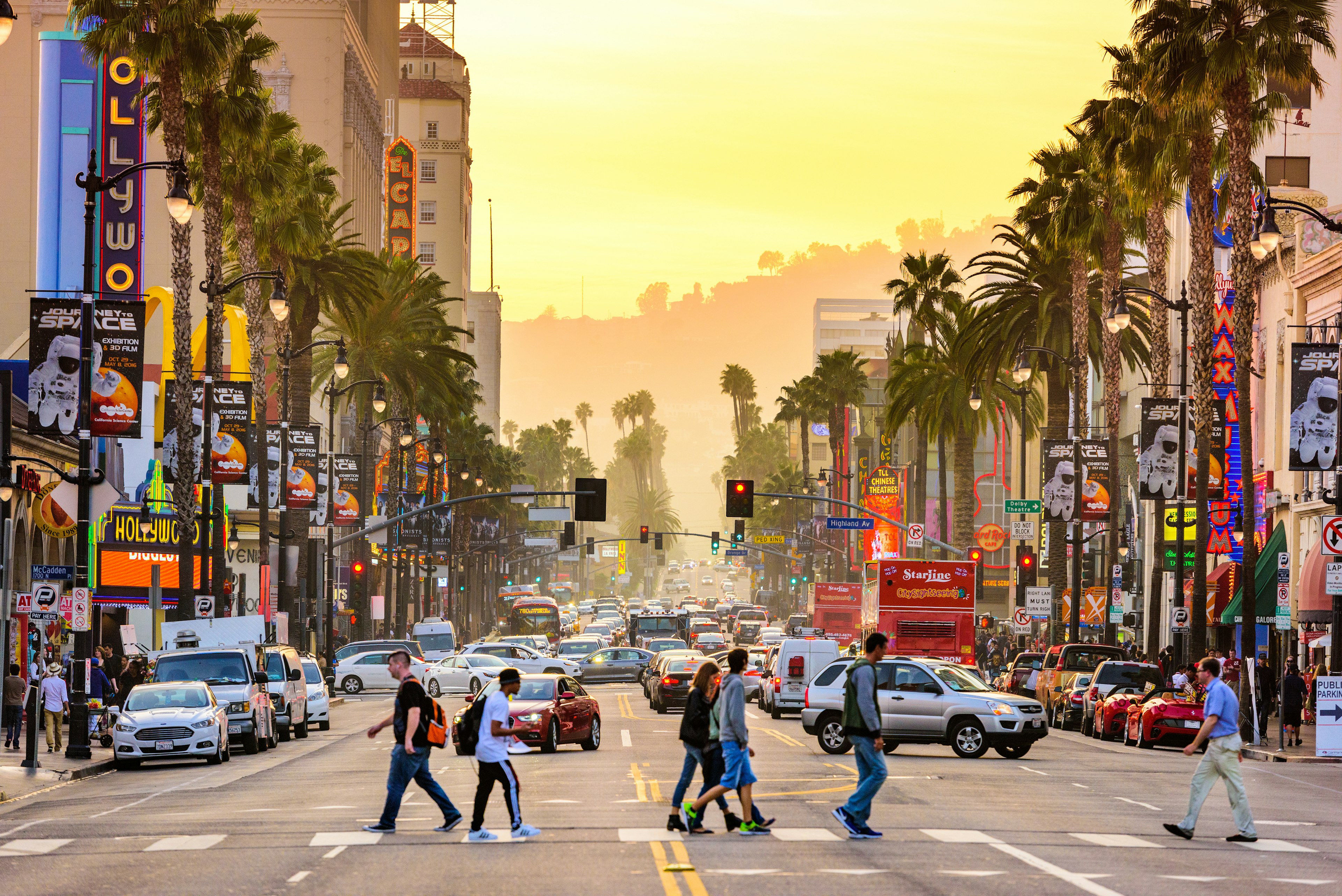 Traffic and pedestrians on Hollywood Boulevard at dusk.