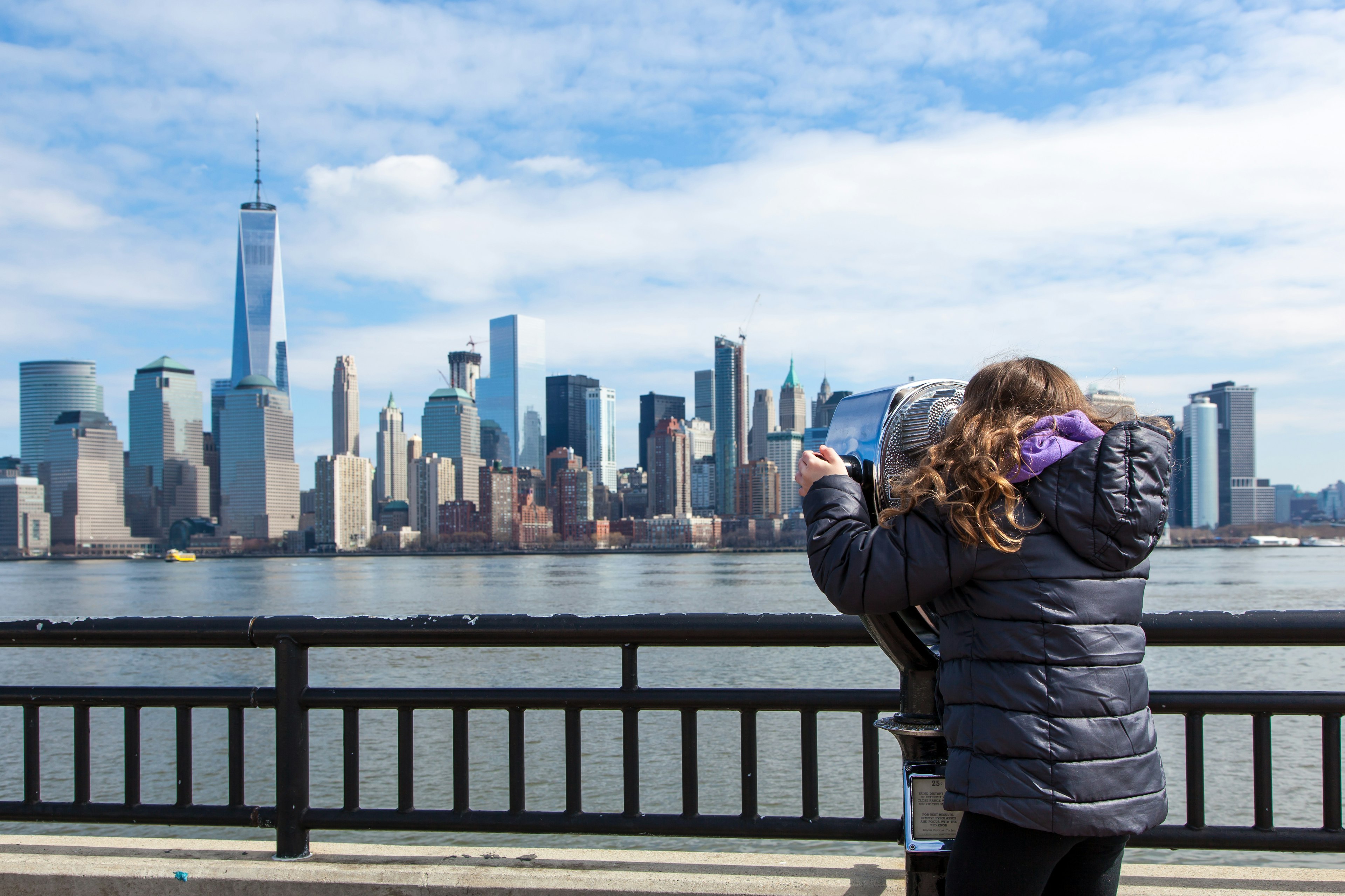 A little girl looks at the Manhattan skyline through binoculars at Liberty State Park