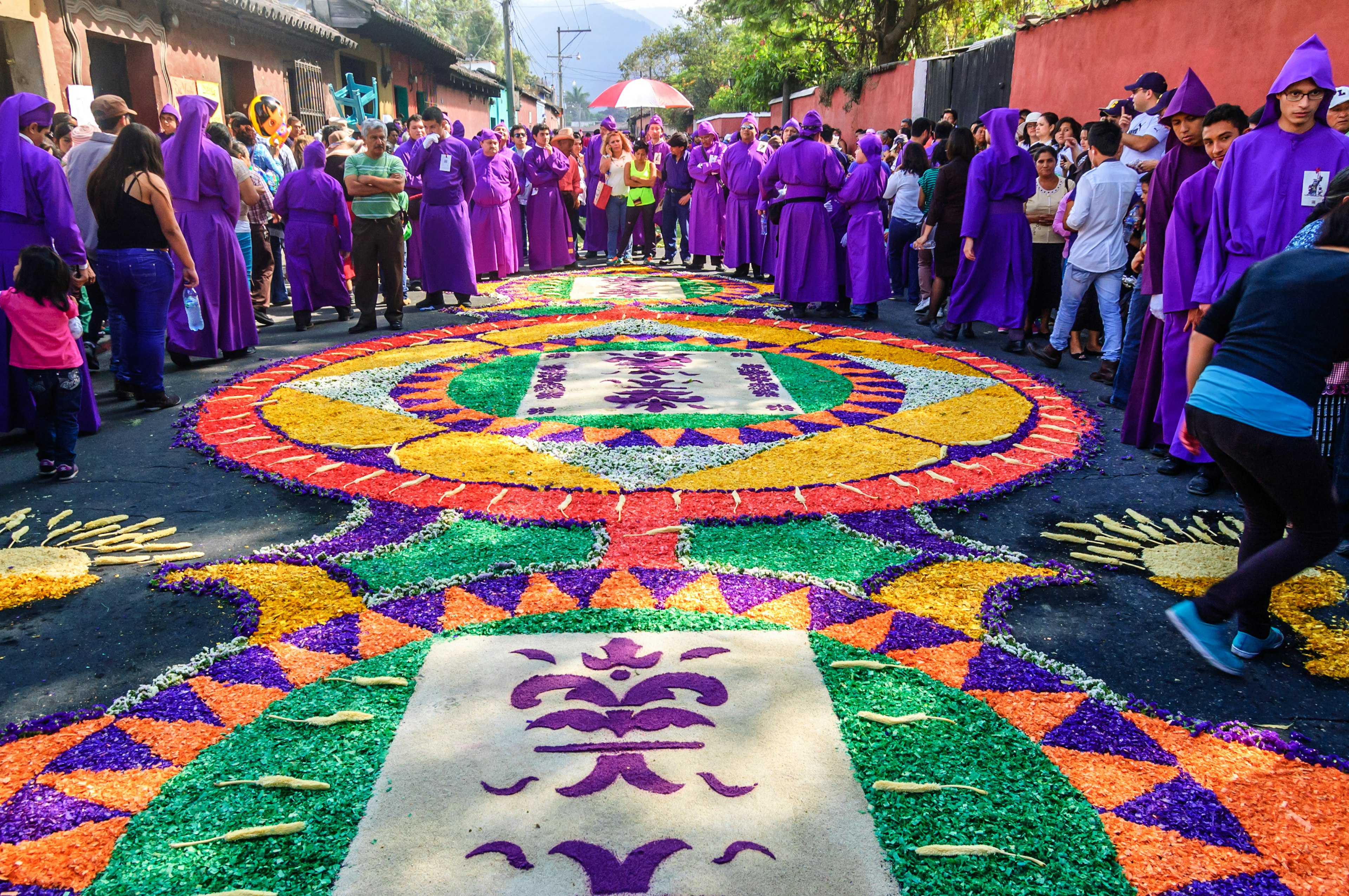 Onlookers & float bearers admire dyed sawdust patterns in the streets of Antigua, Guatemala, during Semana Santa.