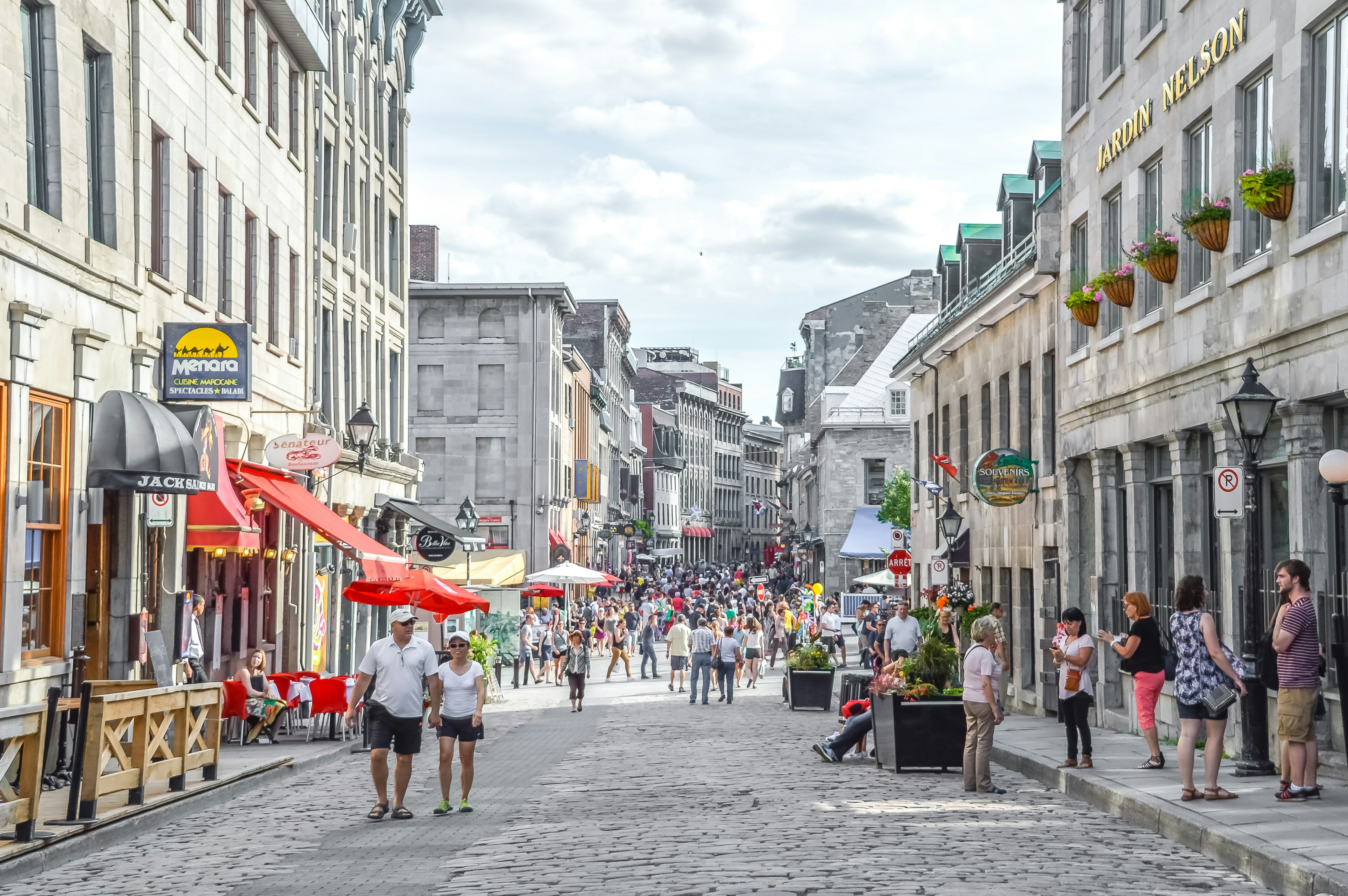 People wonder along the cobbled streets of St Paul Street in Old Port, Montreal. It is a sunny day and people are in shorts and sunglasses