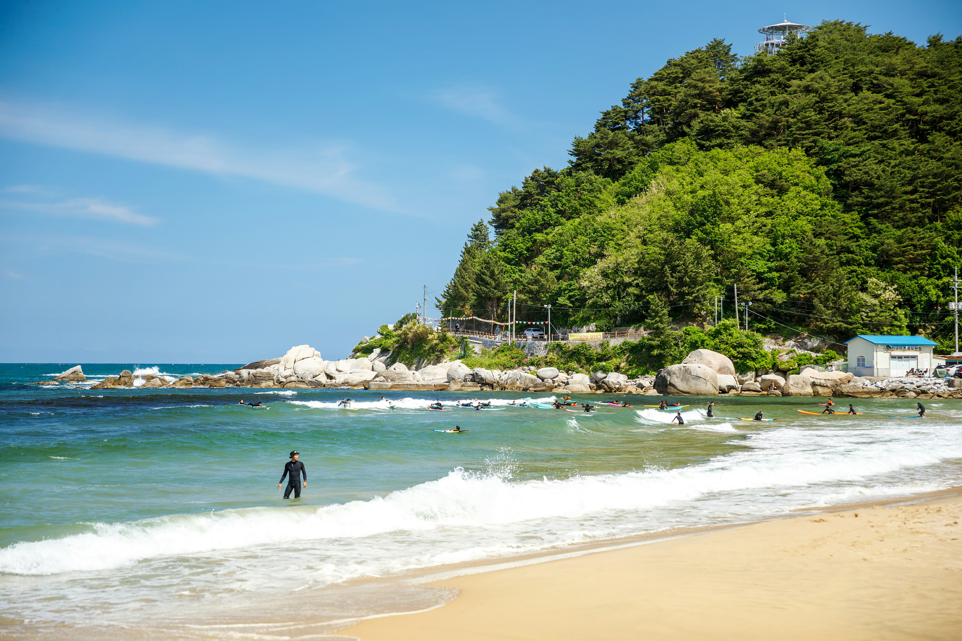 A surfer pushing his board into the sea at Jukdo Beach, South Korea