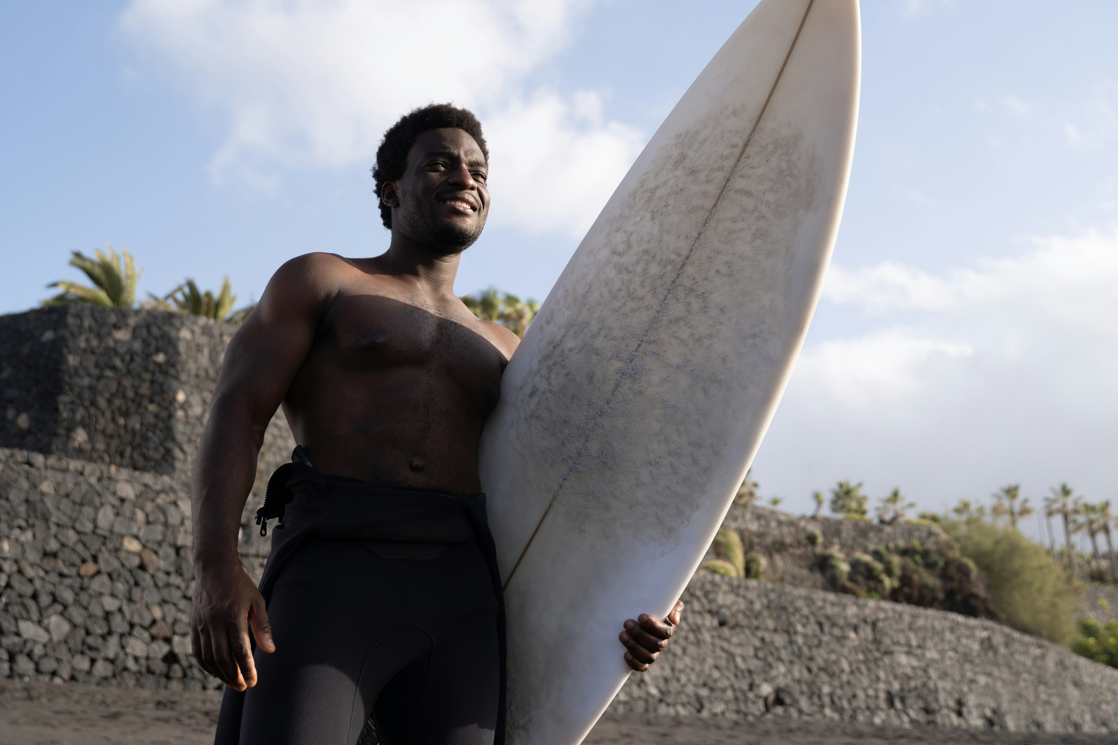 Man holding a long surf board on a beach in Tenerife, Canary Islands, Spain