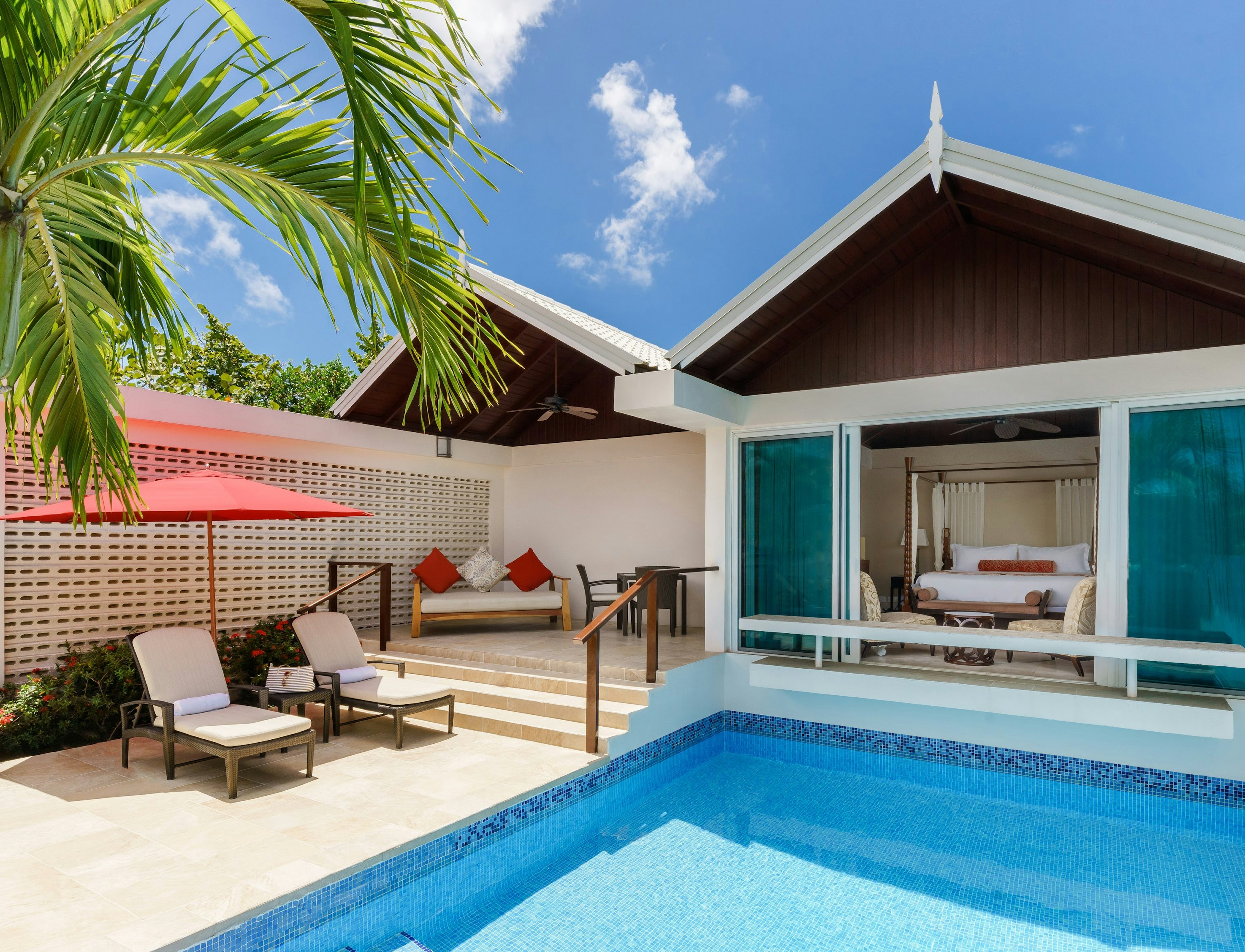 A pool right outside the door to a private villa, surrounded by sun loungers and a privacy screen