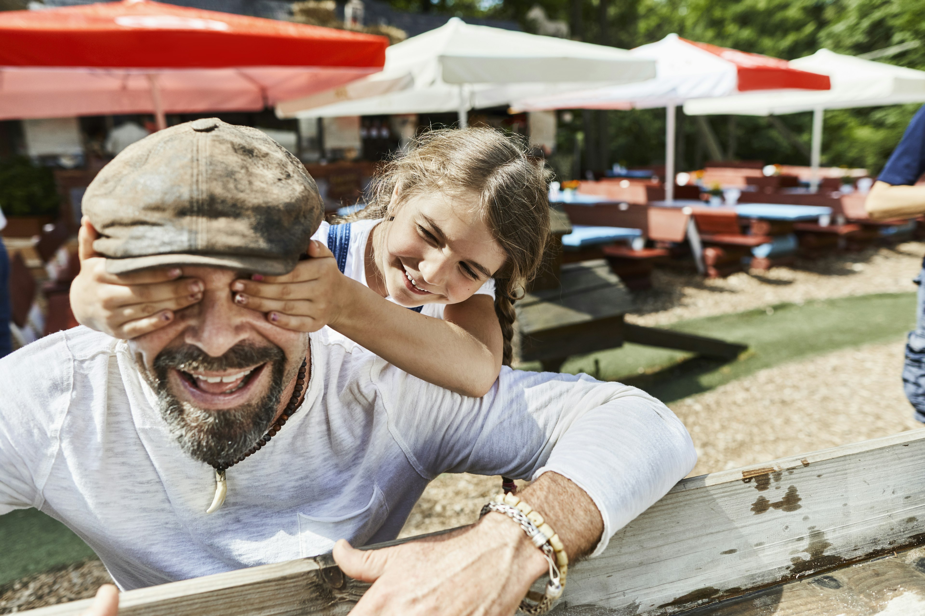 Daughter covering father's eyes on a playground