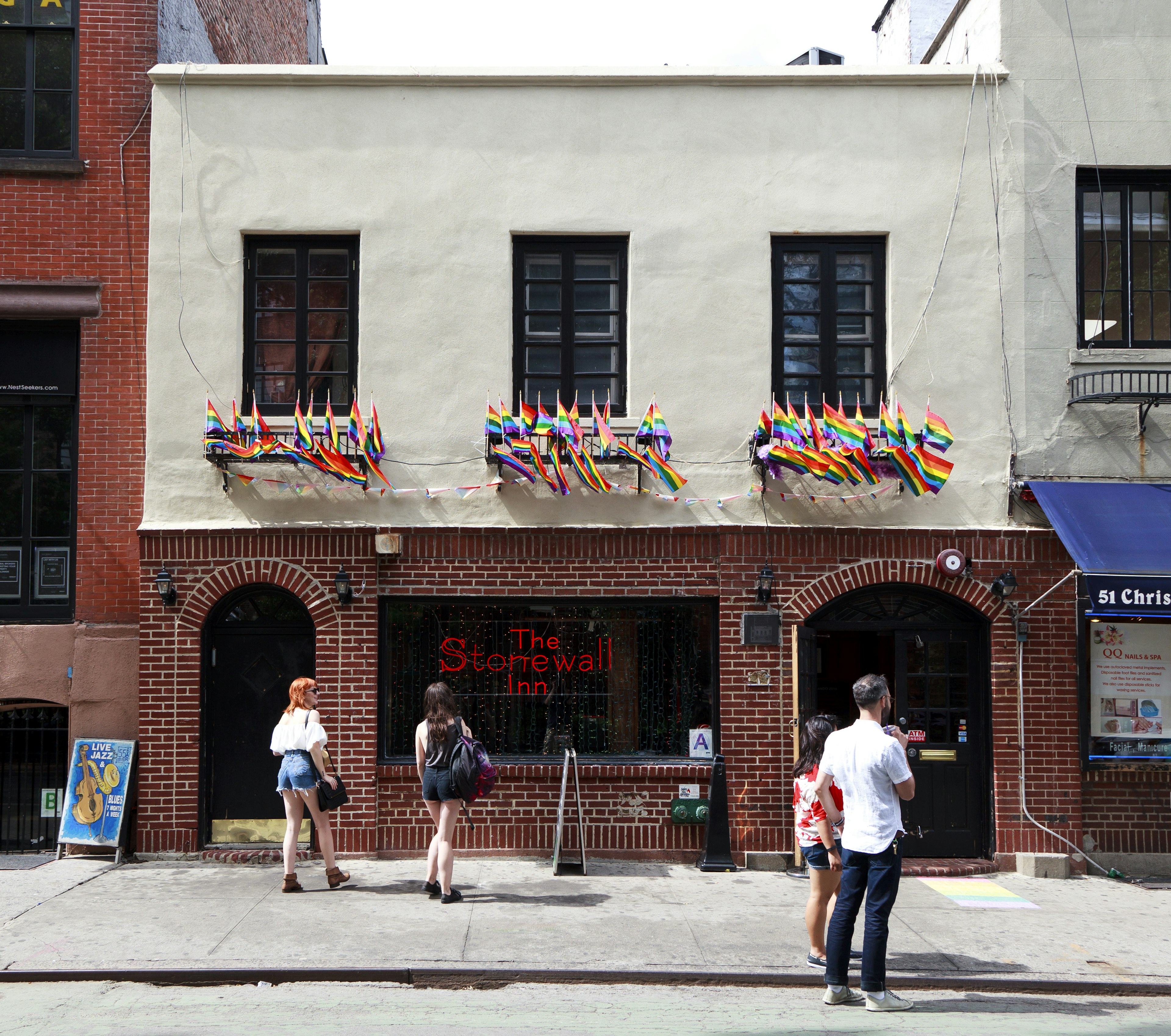 The exterior of the Stonewall Inn, a famous gay bar in New York City, with many rainbow flags flying from its walls