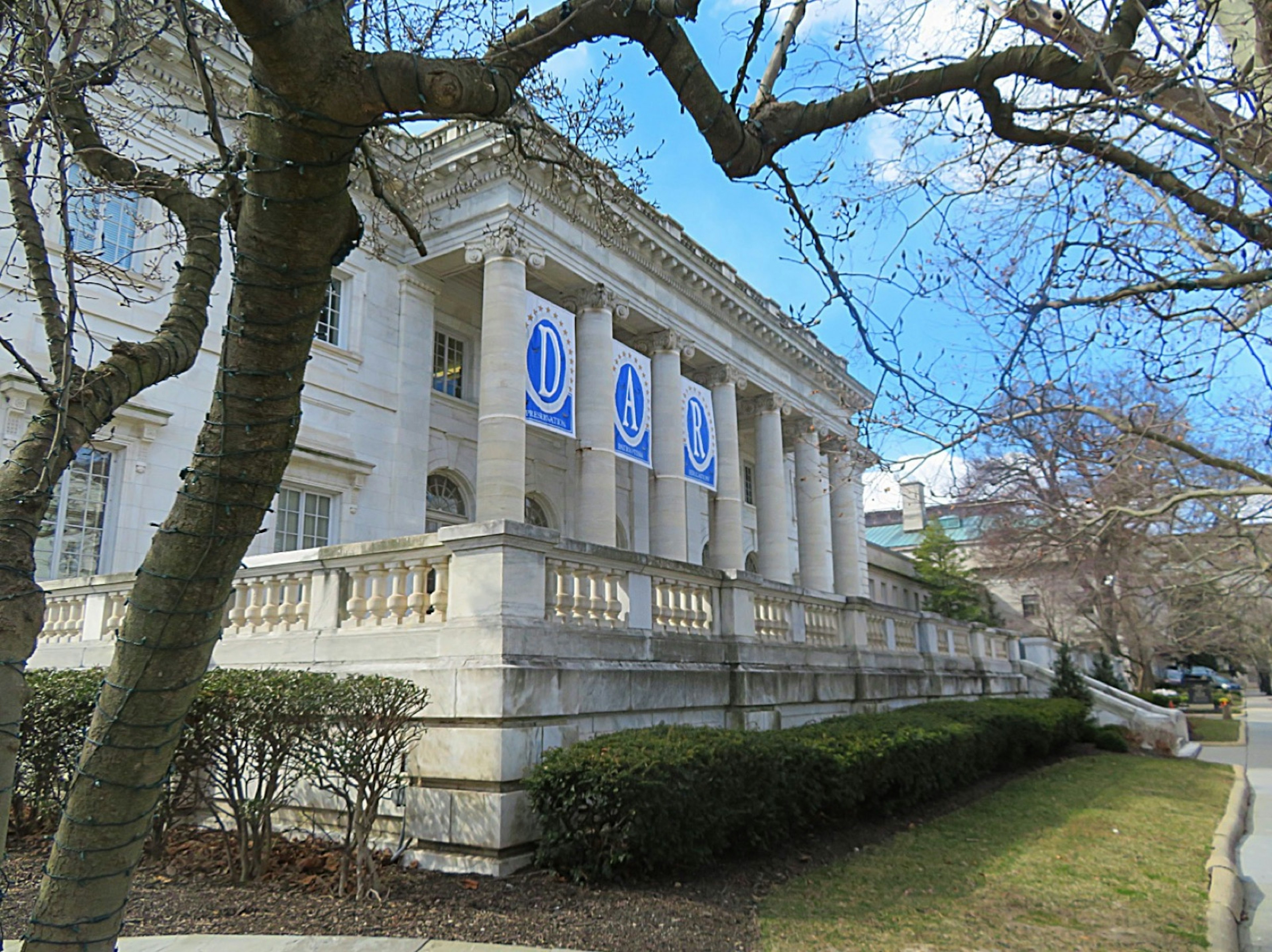 A row of white marble columns holds blue flags that spell the letters D A R.