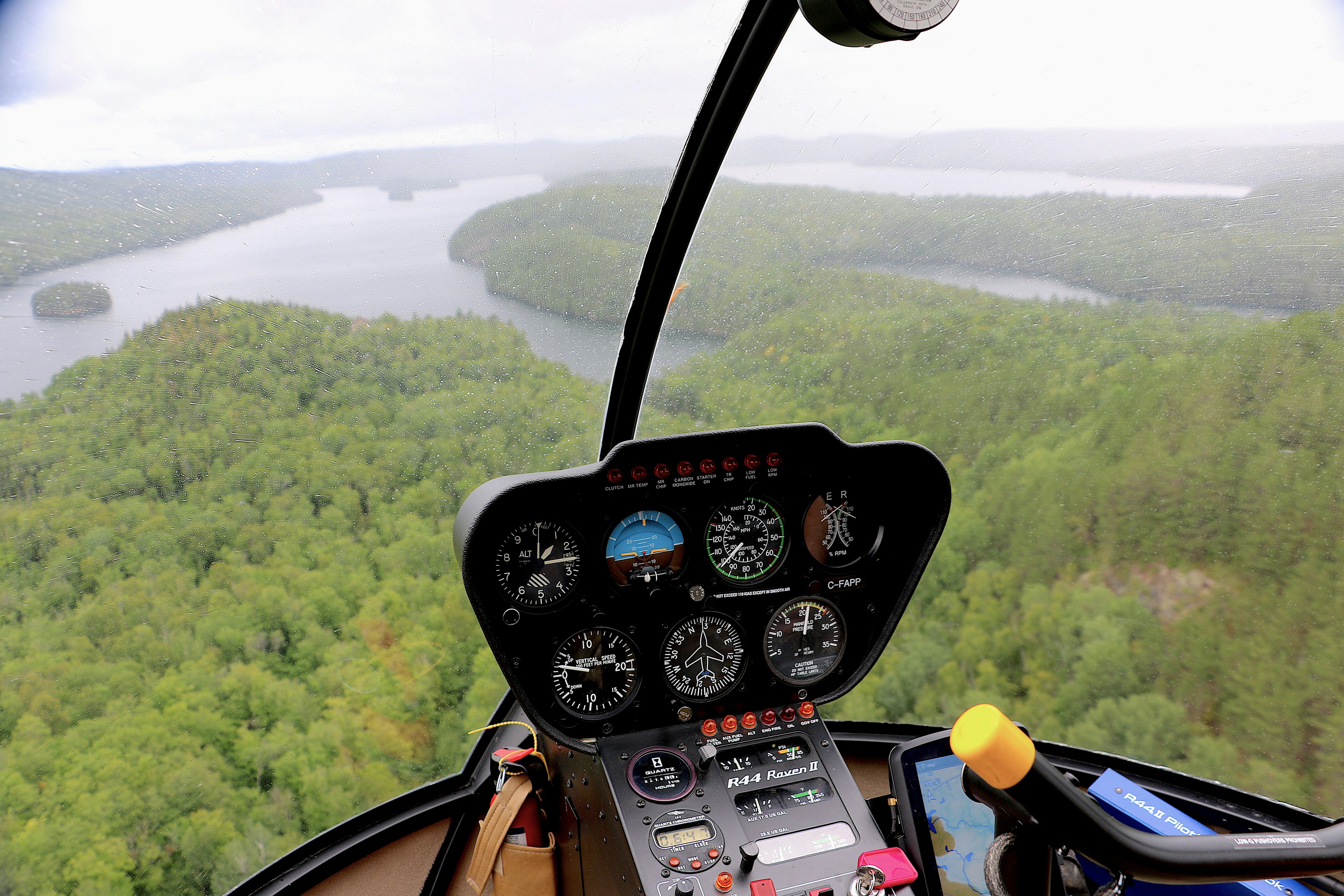 The flight controls of a small helicopter over a wilderness area in Quebec